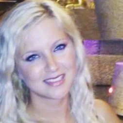 A woman with long, wavy blonde hair smiling at the camera