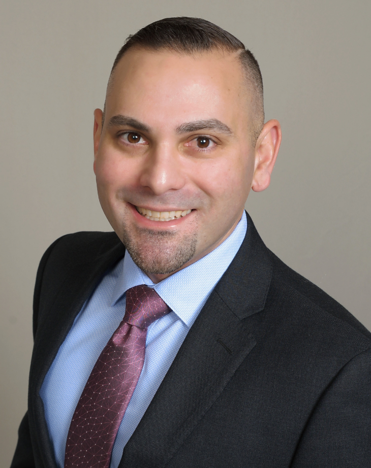 Professional headshot of a man in a suit and tie smiling at the camera.