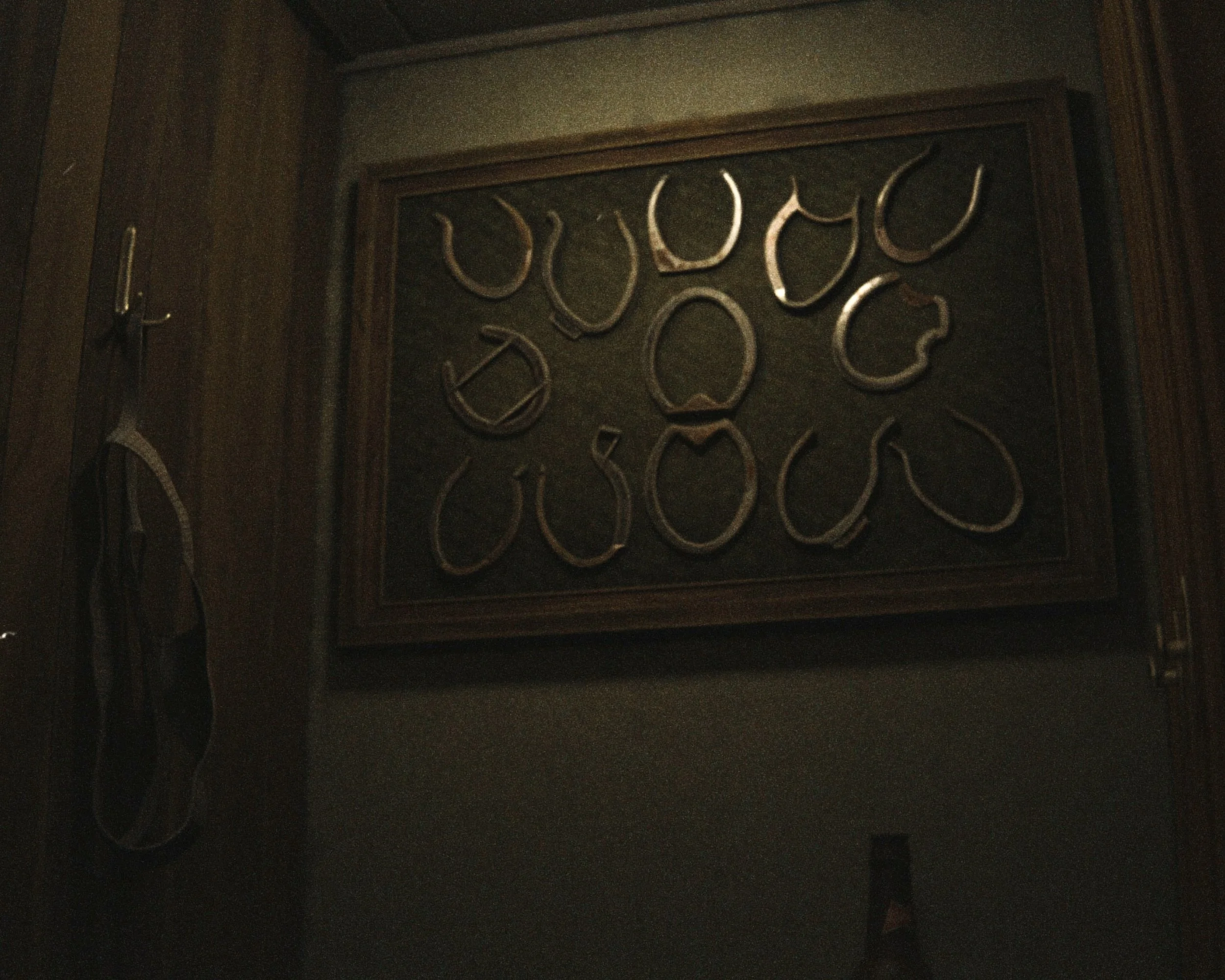 Dark wooden framed display case with metallic outlines of various car parts or mechanical objects inside.