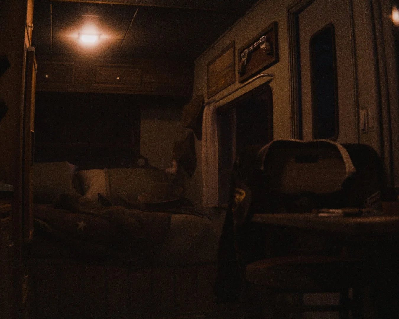 Dimly lit interior of a camper trailer with a couch, table, and stroller.
