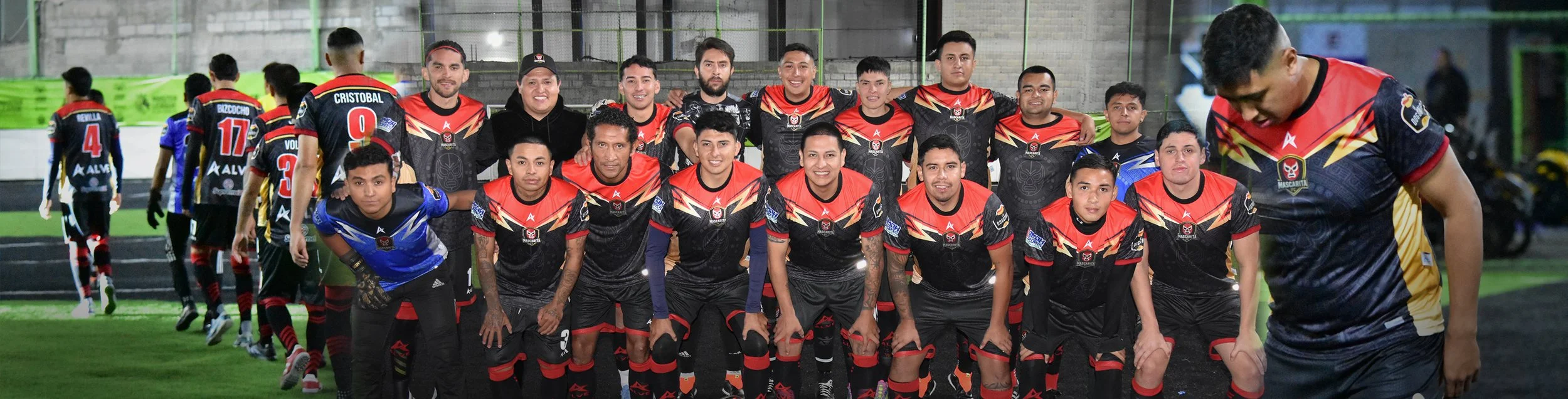 Equipo amateur con uniformes de fútbol personalizados en diseño negro y rojo con números y patrocinadores.