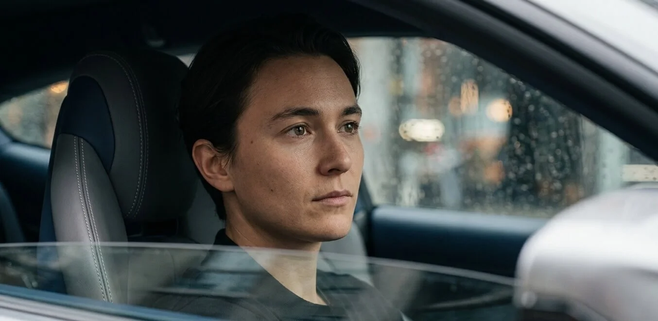 Person sitting alone in a car looking reflective, representing the experience of money anxiety even when financially secure