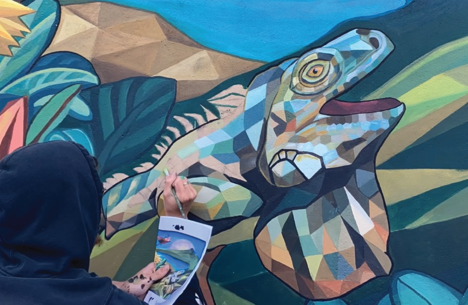 Close-up of a red fabric with a stitched emblem of FC St. Louis, featuring a shield shape, a mountain with sun rays, and a soccer ball with the words "STL