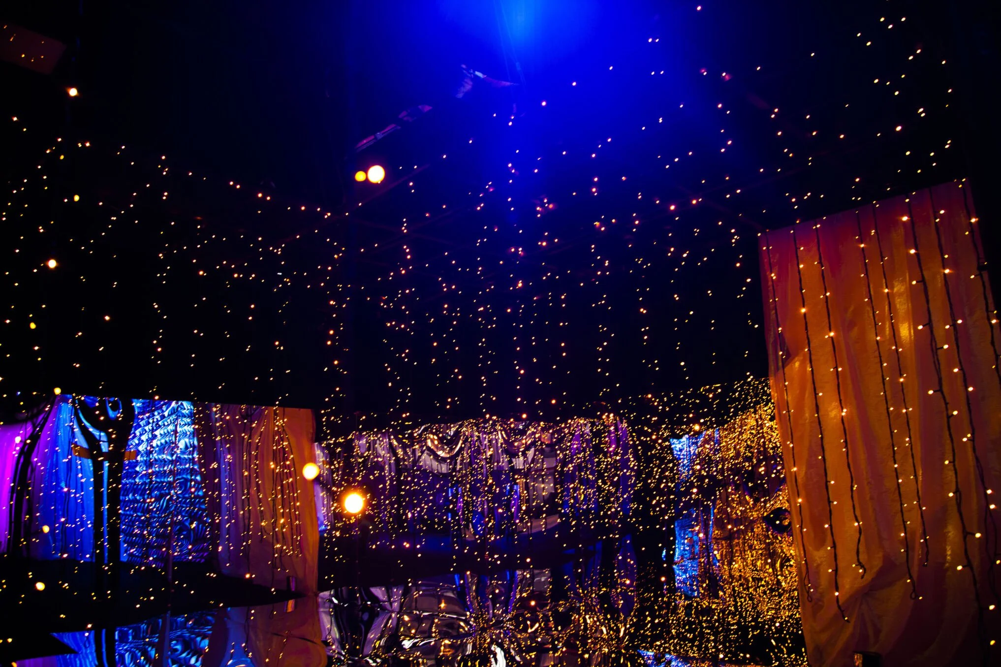 Decorative string lights hanging from the ceiling with reflections on a mirror surface below, creating a festive atmosphere.