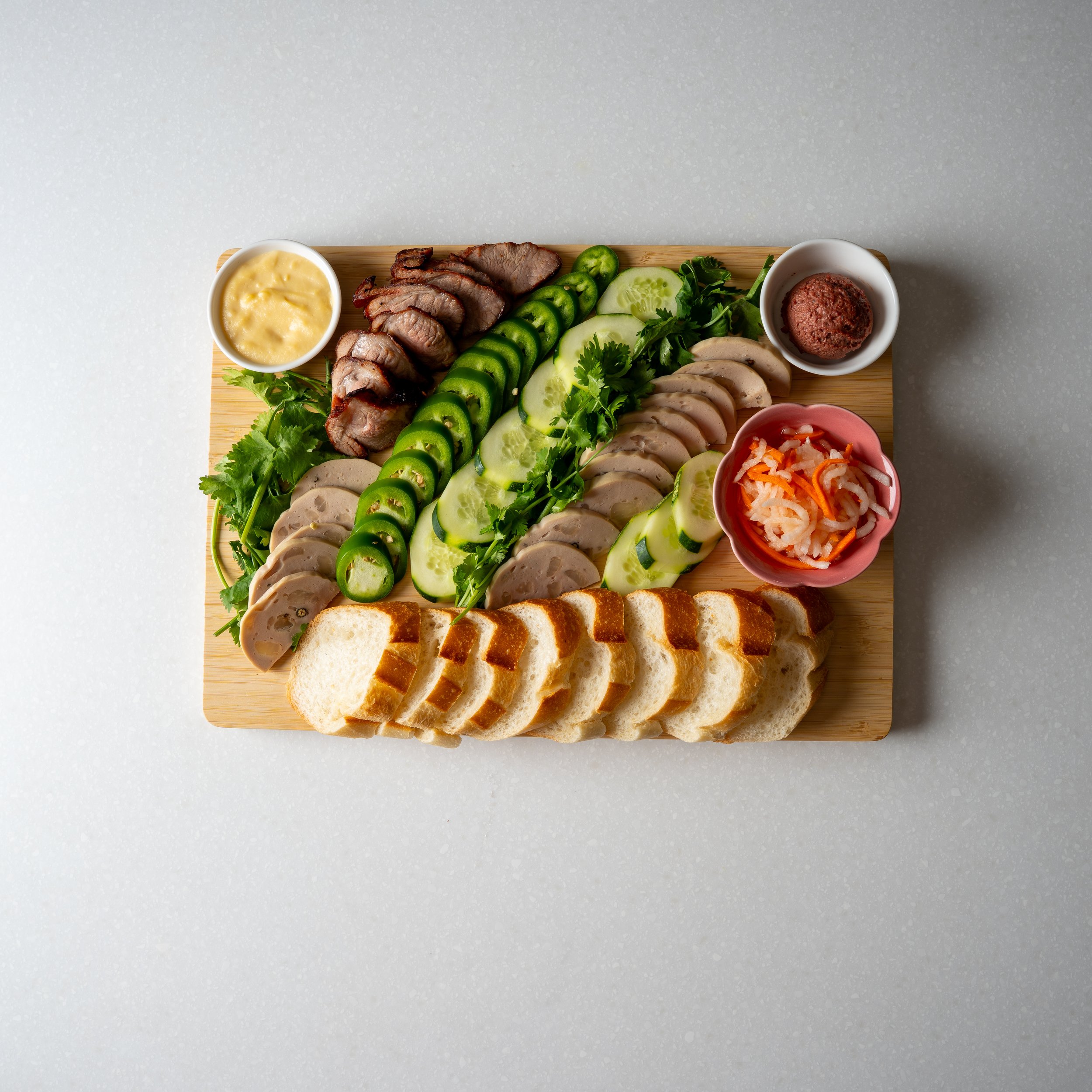 large wooden board filled with sliced vegetables, eggs and pork rinds, very colorful and beautiful, and two sauces for dipping