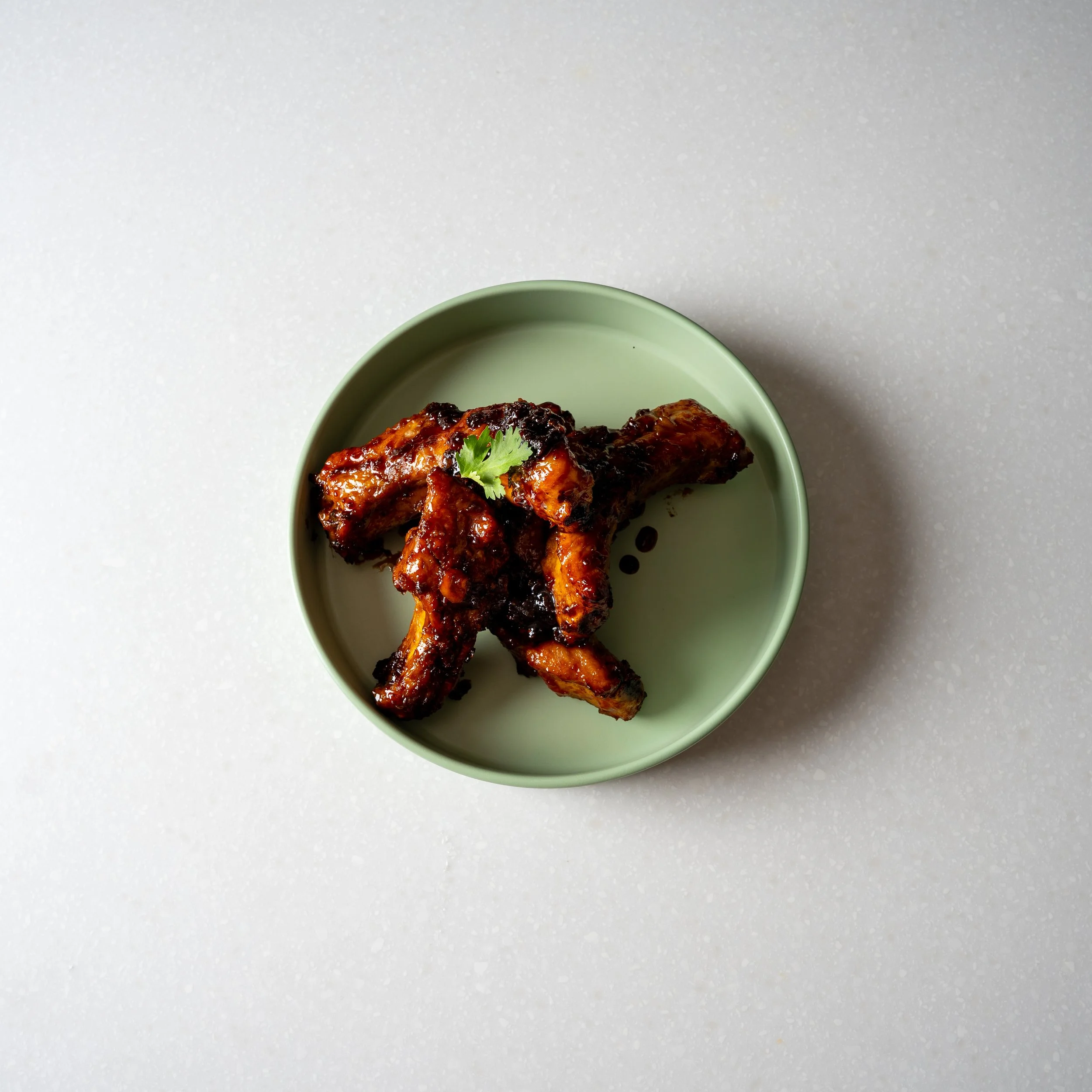 green plate with marinated and grilled chicken pieces with cilantro garnish