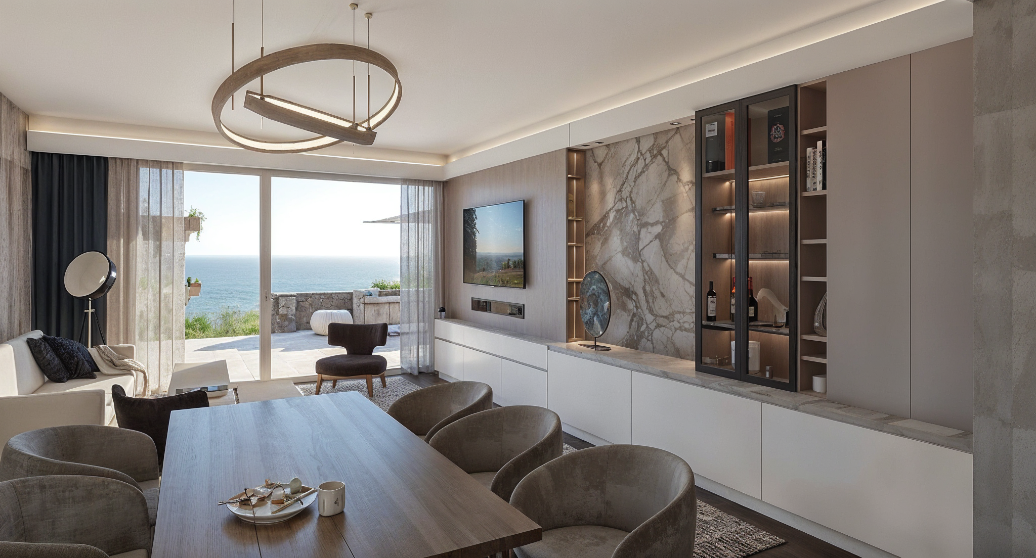Sala de estar moderna con vista al mar, con sofá beige, sillón oscuro, mesa de centro, muro con pared de mármol, televisor, y ventanales grandes que abren a una terraza exterior con vista al océano.