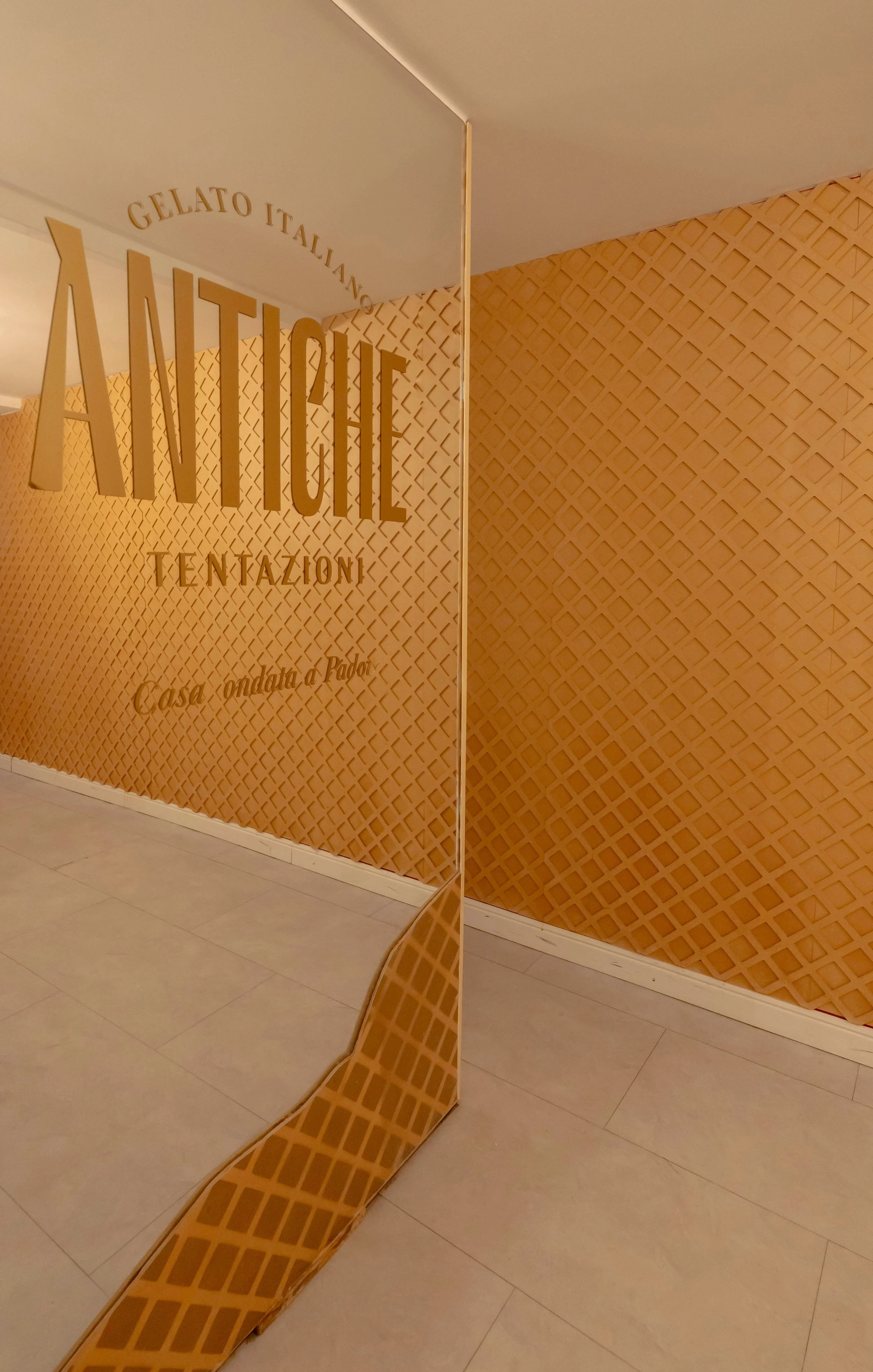 Letrero en el muro que dice 'Gelato Italiano Aniche Tentazioni' con texto adicional 'Casa creada a mano por Radel'.