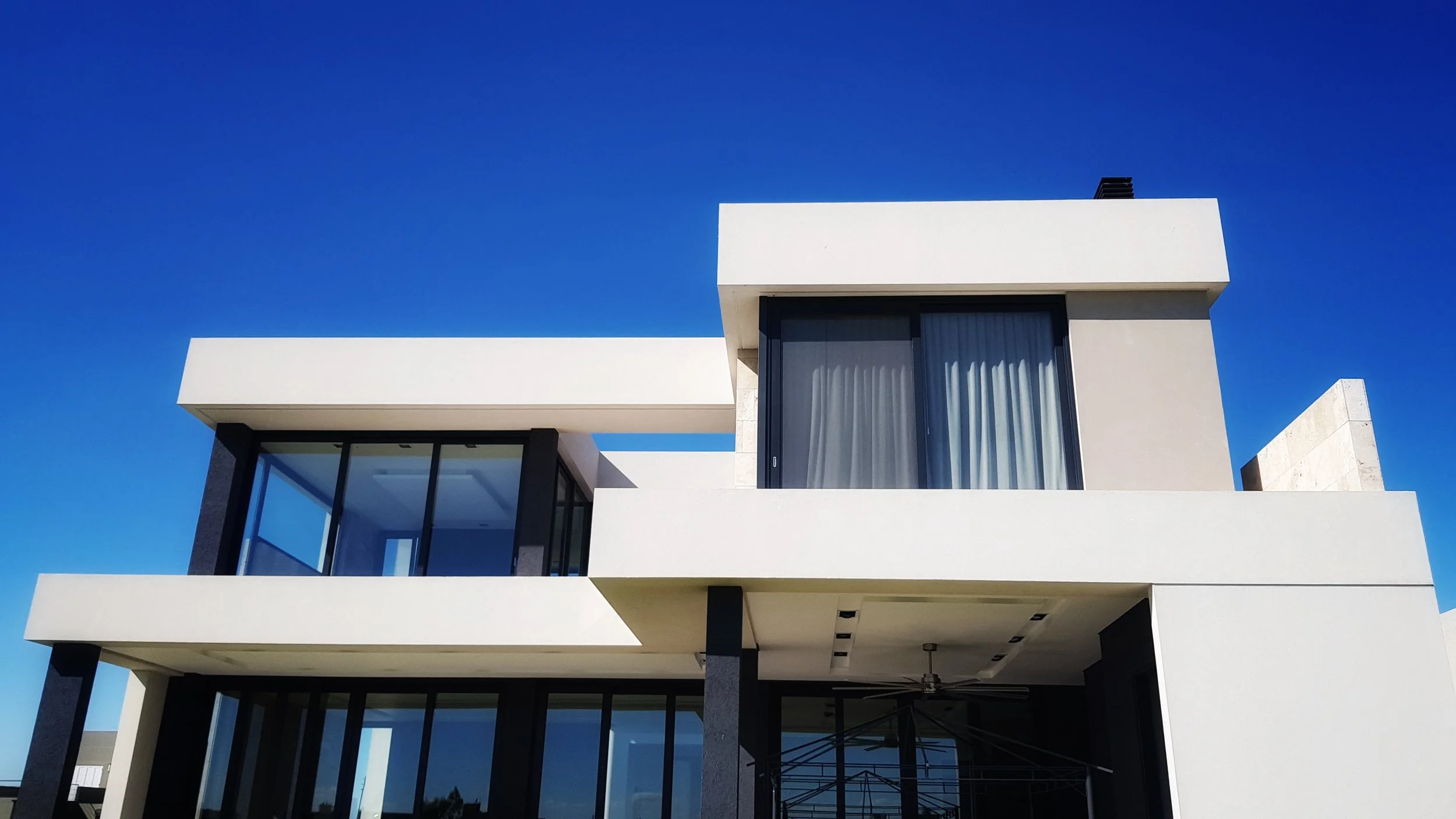 Moderno edificio de varias plantas con grandes ventanas de cristal y líneas rectas, bajo un cielo azul