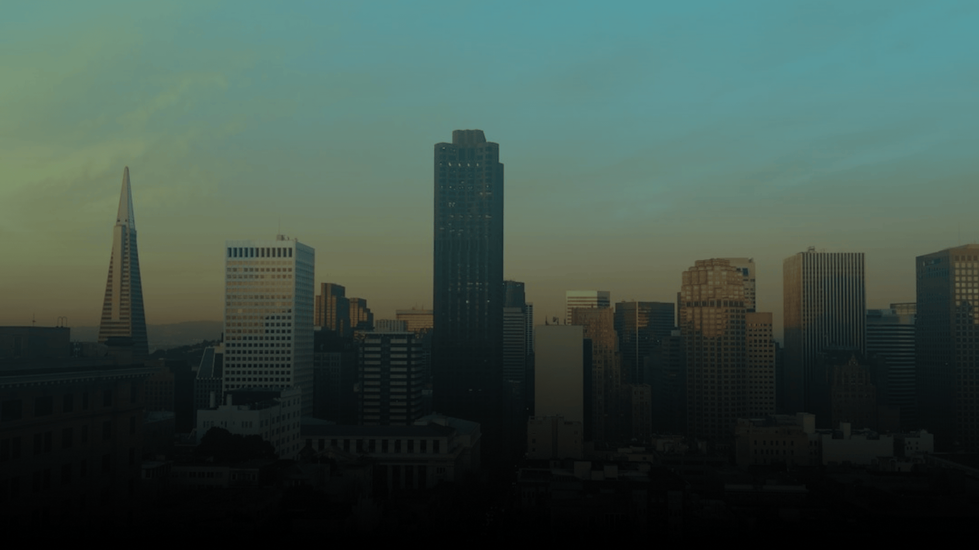 City skyline with tall buildings and a gradient sky at sunset.