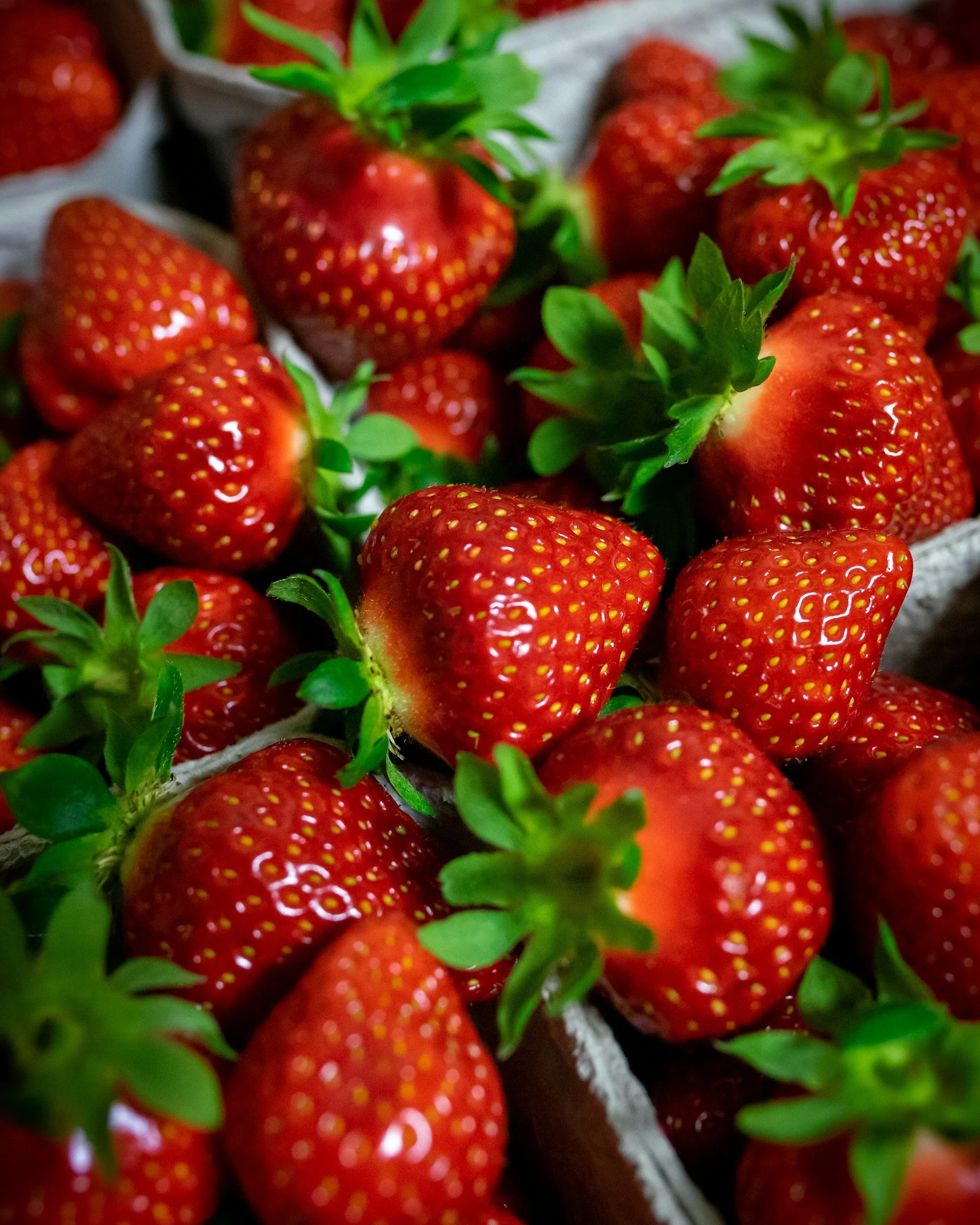 Close-up of fresh, ripe strawberries with green leaves in a basket.