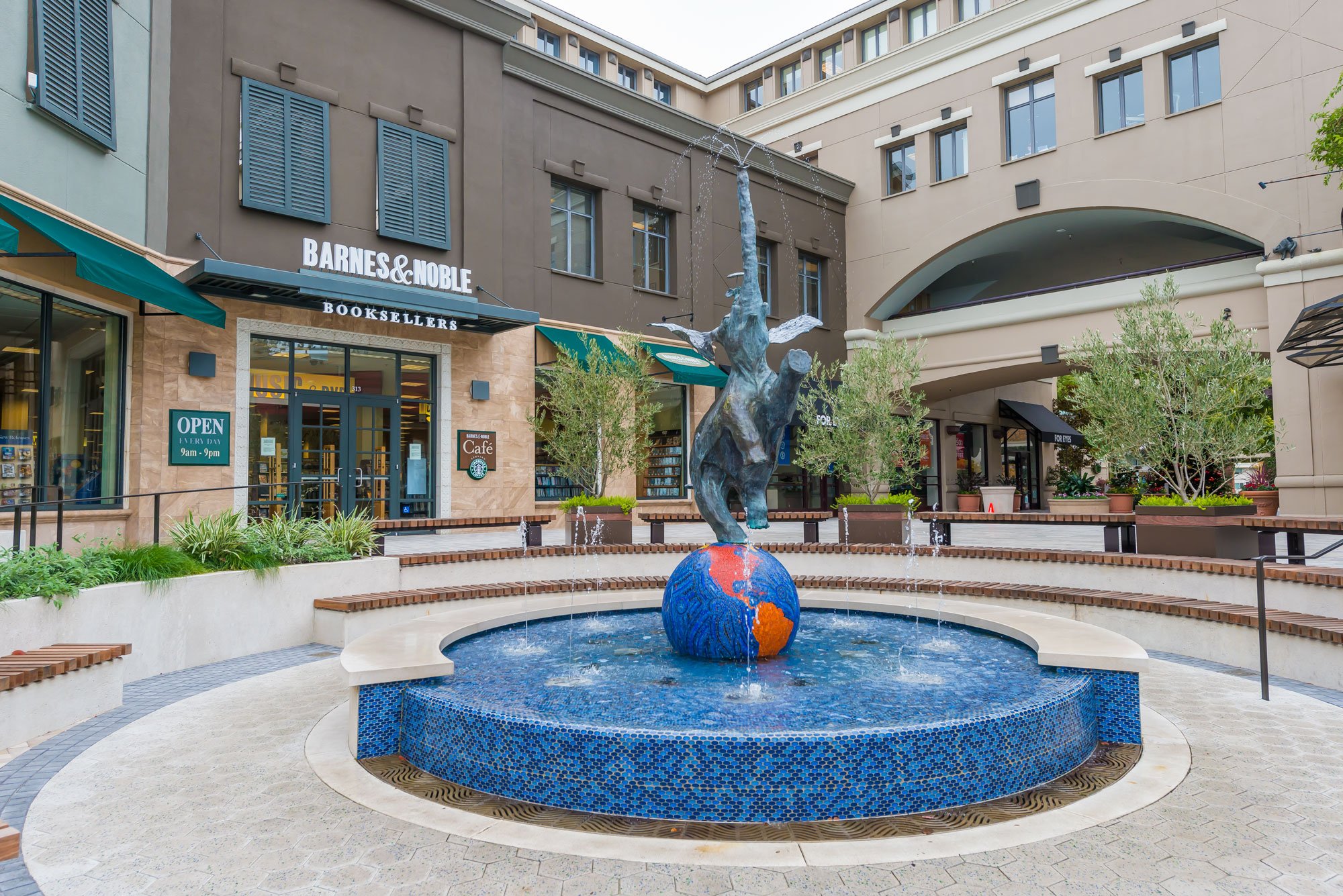 Barnes & Noble bookstore entrance with a fountain featuring a globe and elephant statue in an outdoor shopping area.