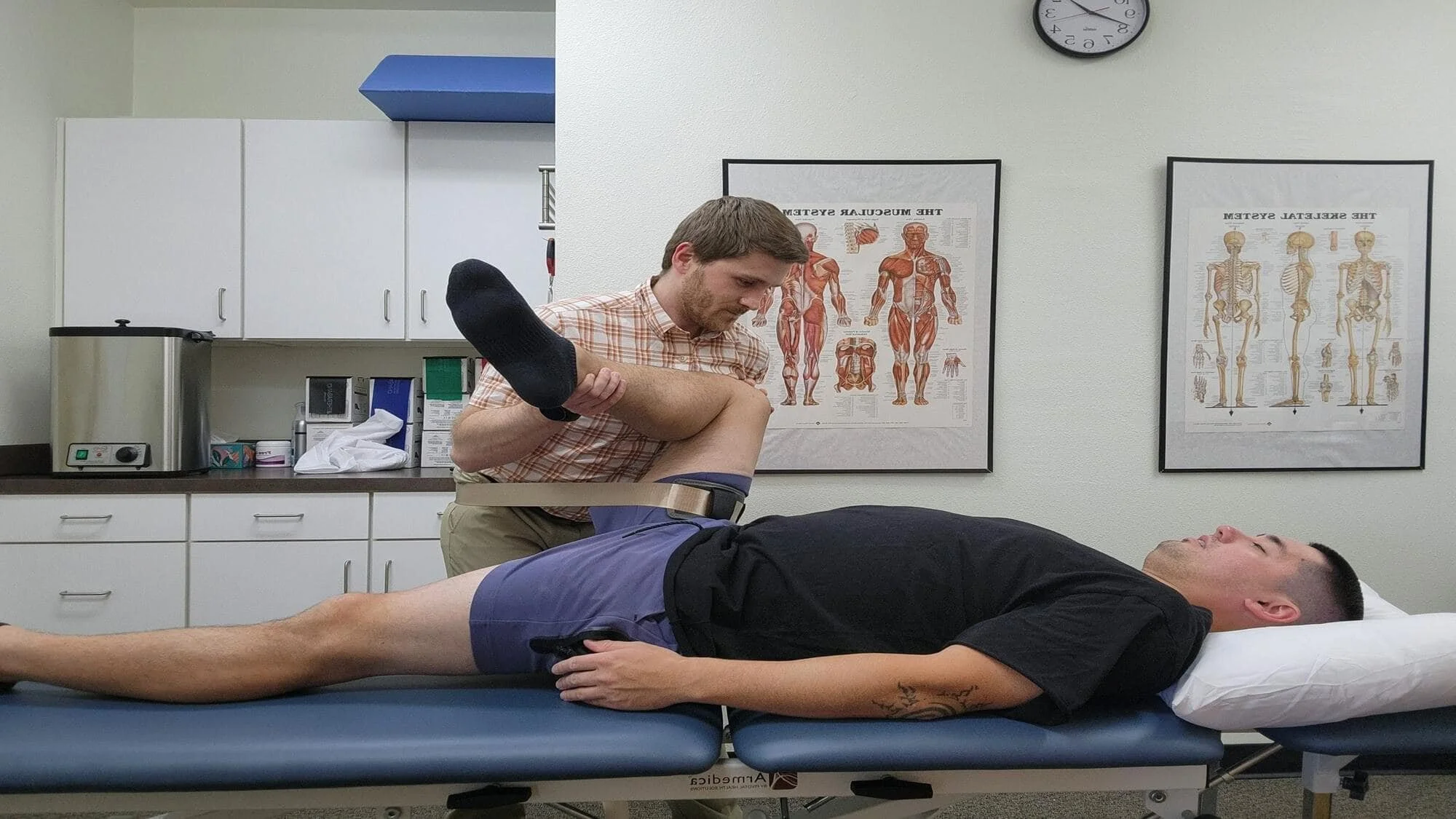 A physical therapist mobilizing a patient's hip using a mobilization belt to increase mobility and reduce restrictions causing pressure on the sciatic nerve.
