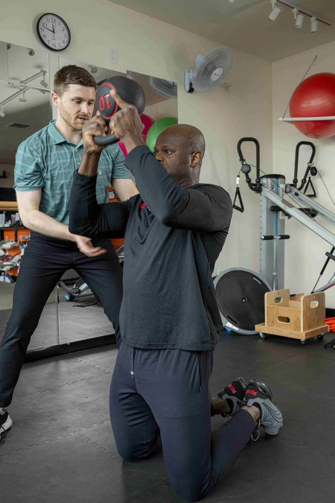 A physical therapist guarding a patient as they perform shoulder halos with a kettlebell for rotator cuff pain treatment in Hillsboro, OR