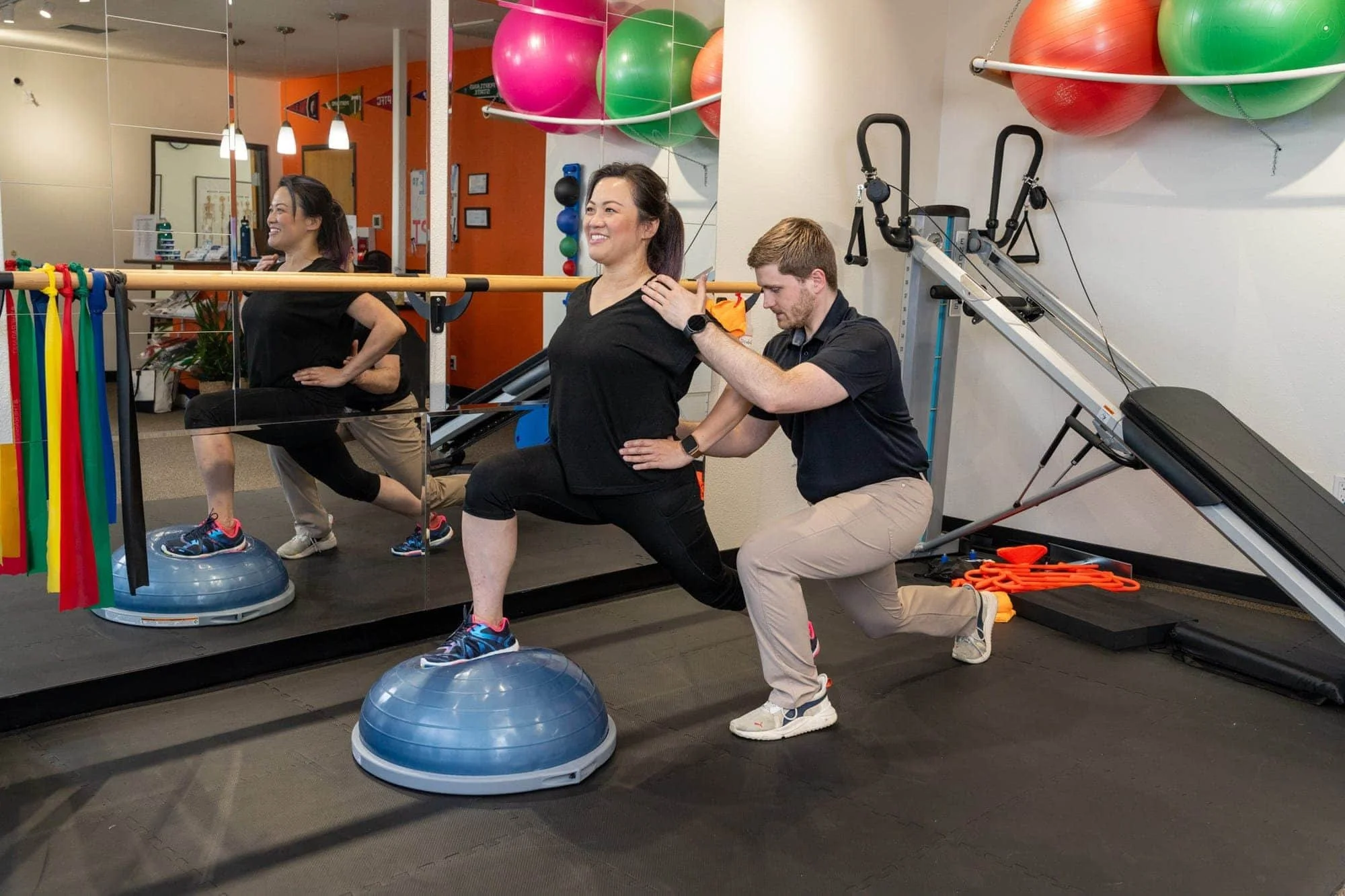 Dr. Ben, physical therapist, assists a patient as they perform a lunge on a BOSU ball for knee stability to prevent knee pain for runners, athletes, lifters, and surgical recovery.