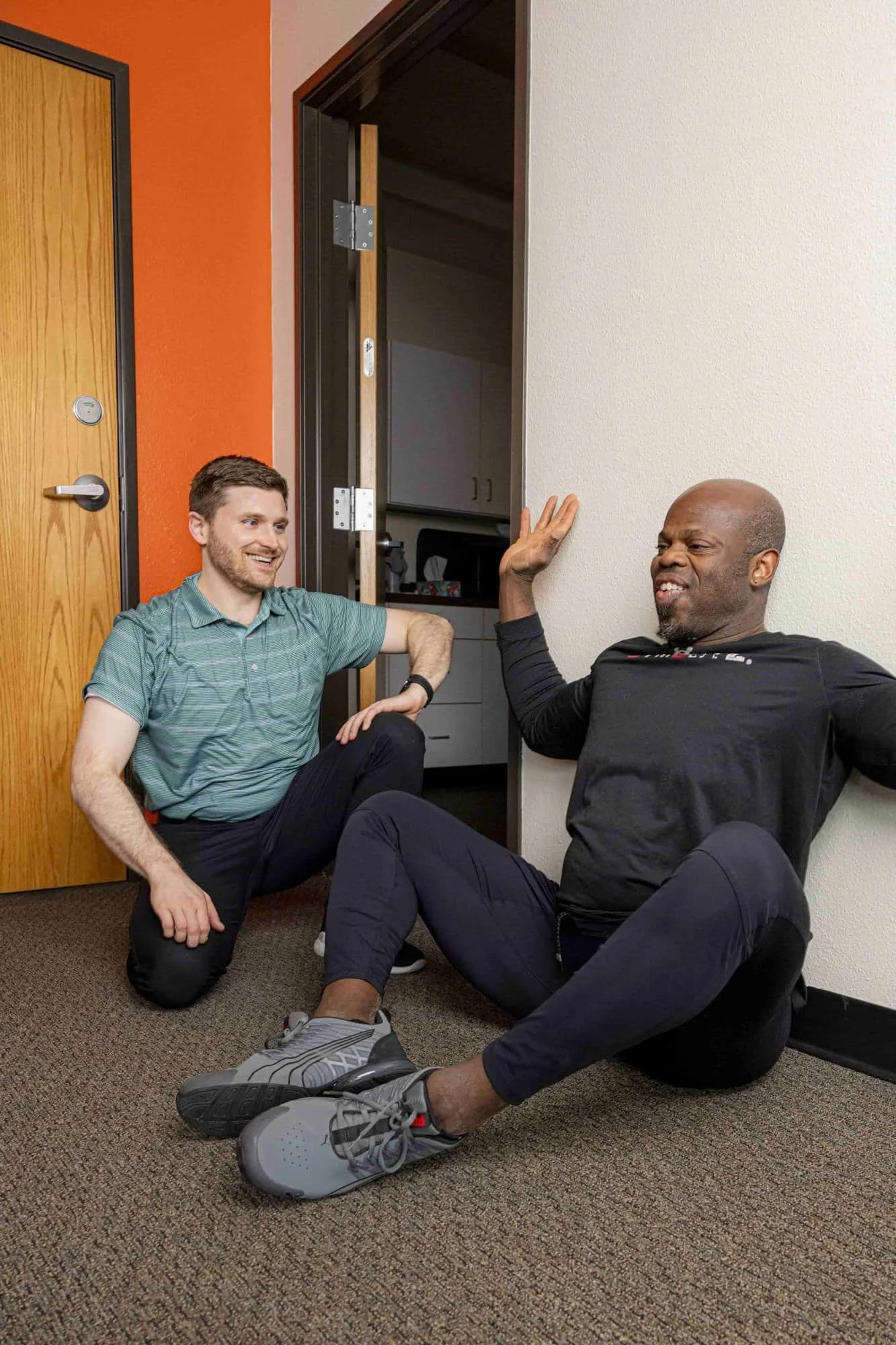 A physical therapist helps a patient with their shoulder mobility as they joke around and have fun while doing so.