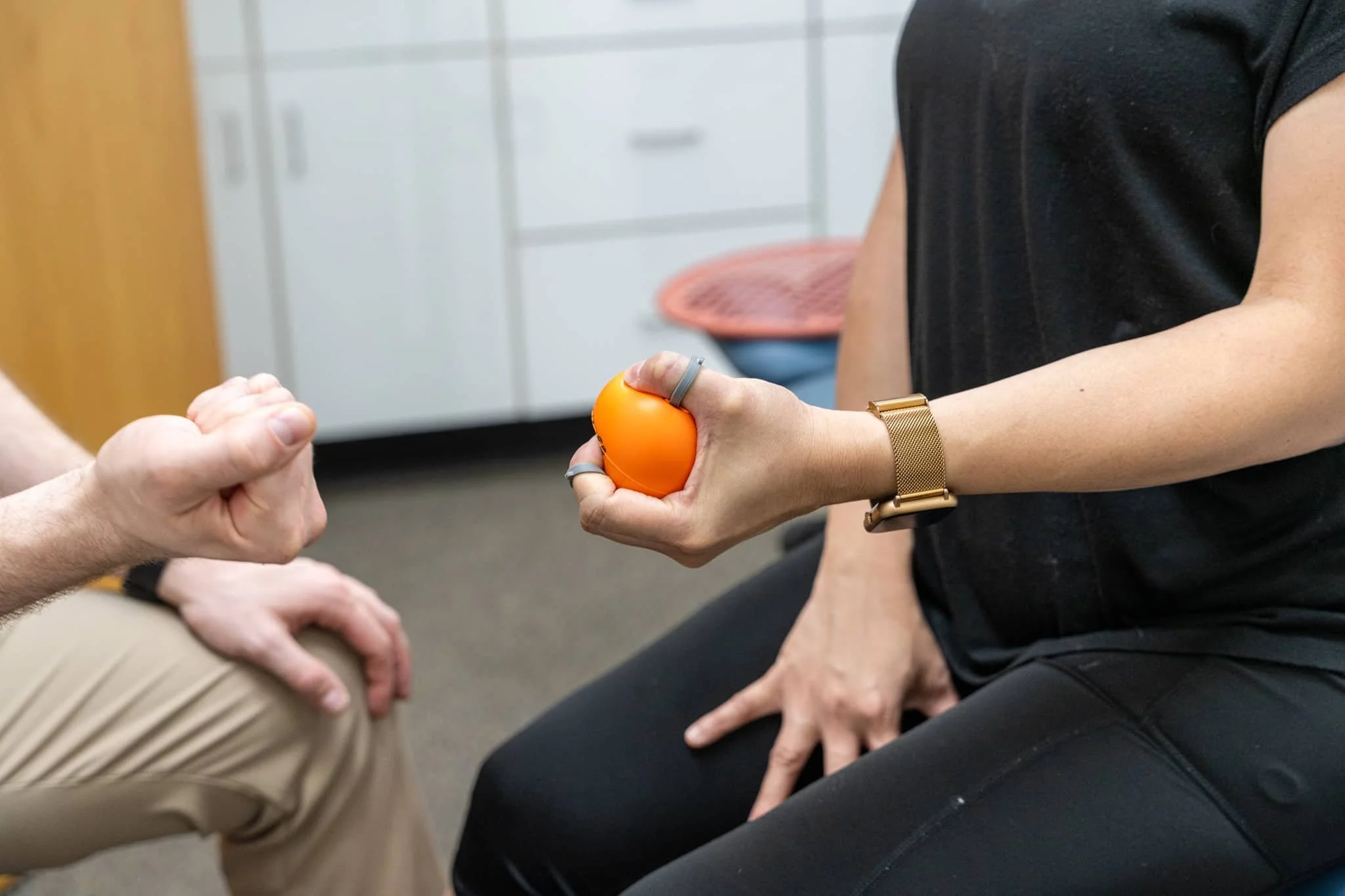 A physical therapist demonstrating a finger flexion exercise for grip strength to help treat golfer's elbow pain