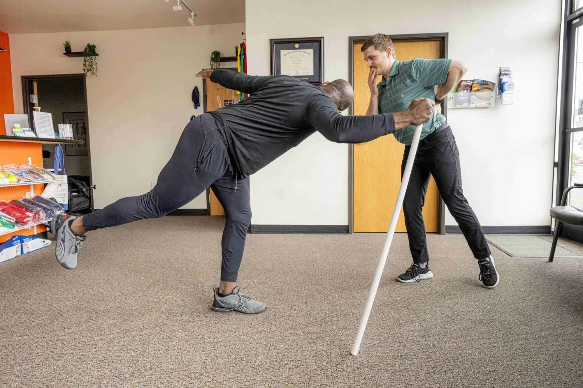 A physical therapist assesses a patient's ability to perform a single-leg hip hinge
