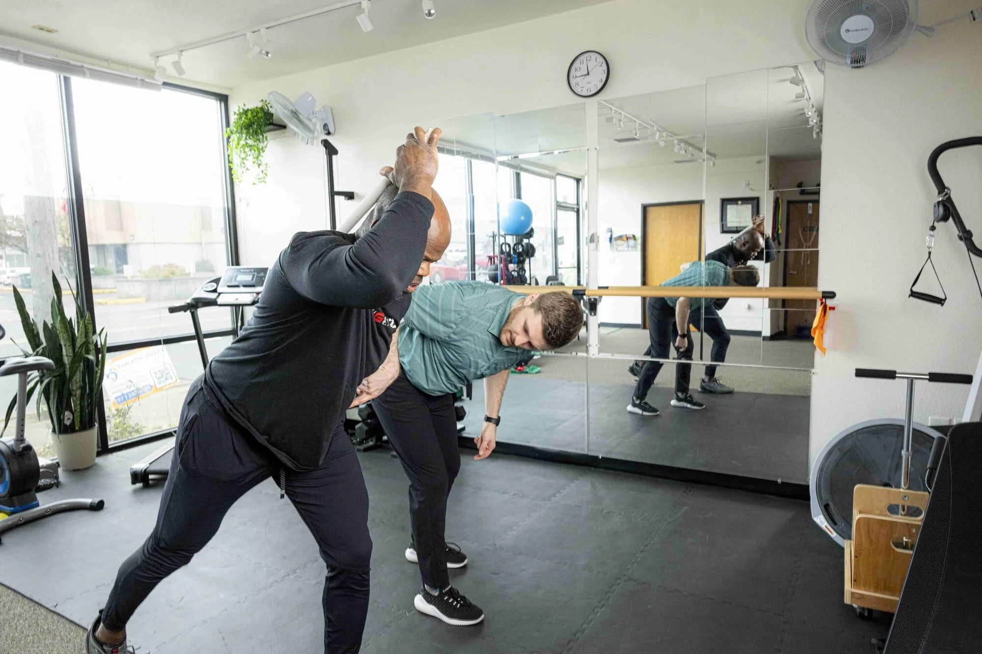 A physical therapist guiding a man dressed in black on using their gluteal muscles in an assessment for runners