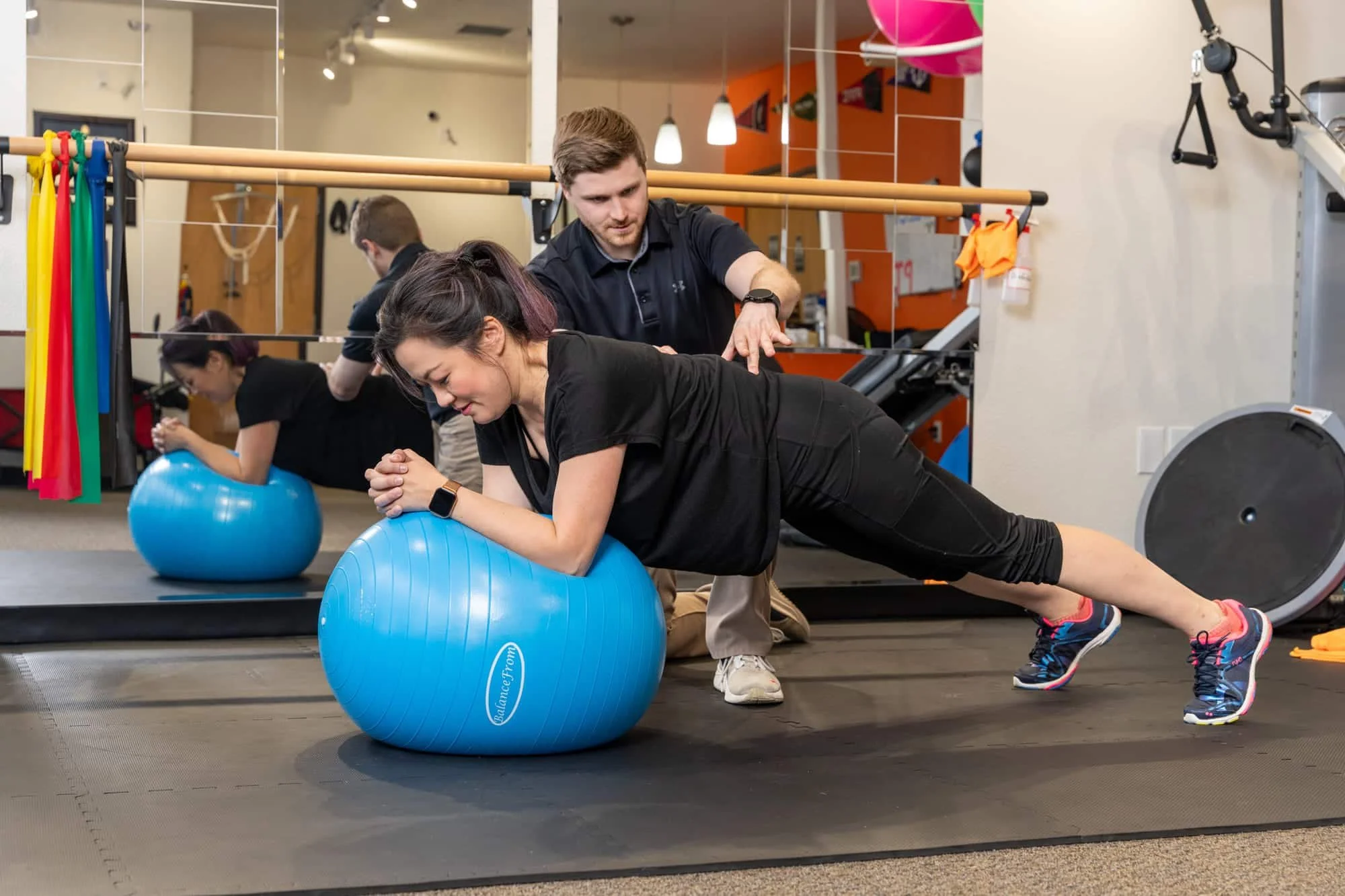 A physical therapist working with a patient on their core and low back stability on an exercise ball for added should.er stability to prevent injury