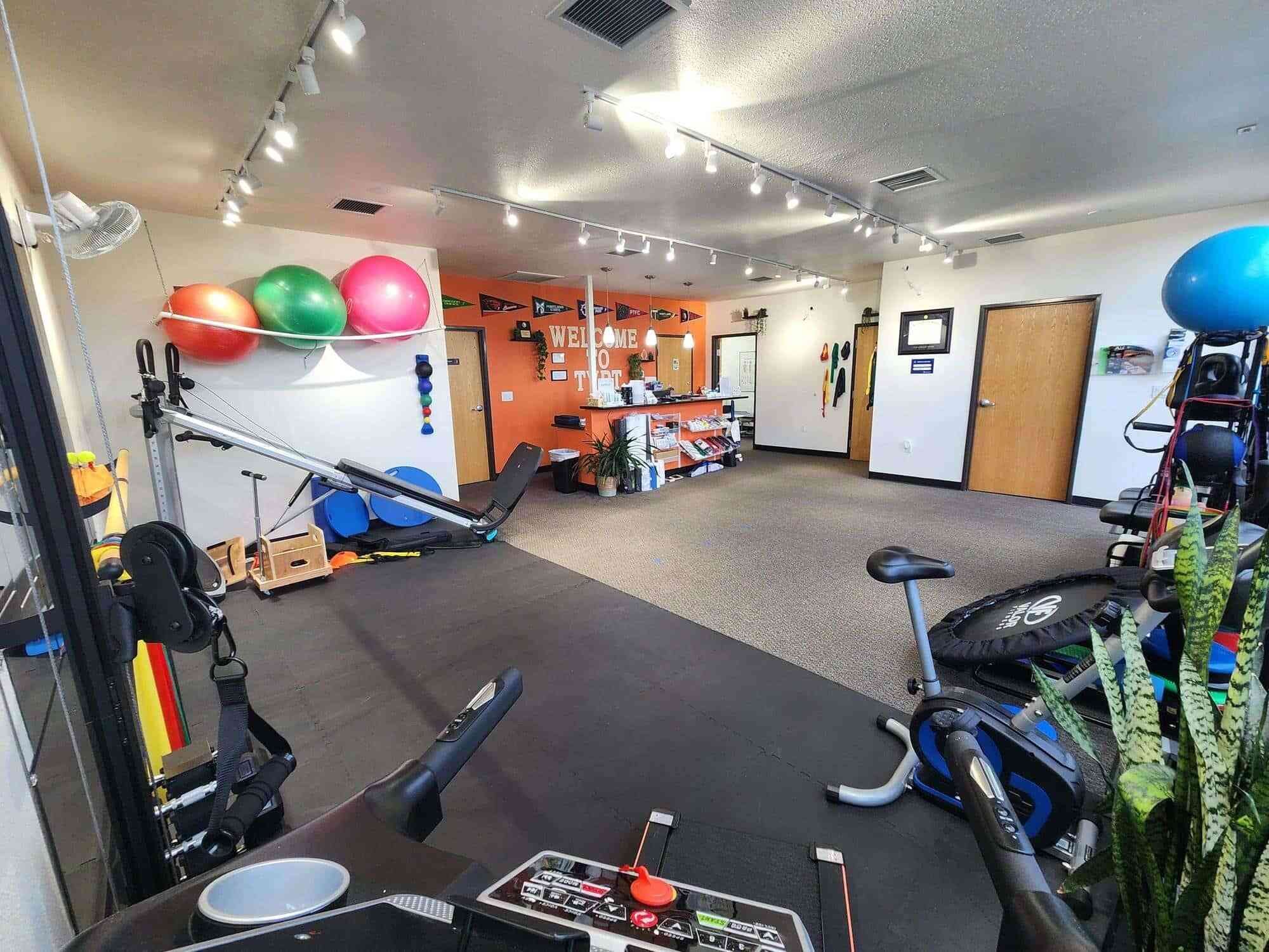 Interior of a PT clinic with various exercise equipment and colorful stability balls on the wall.