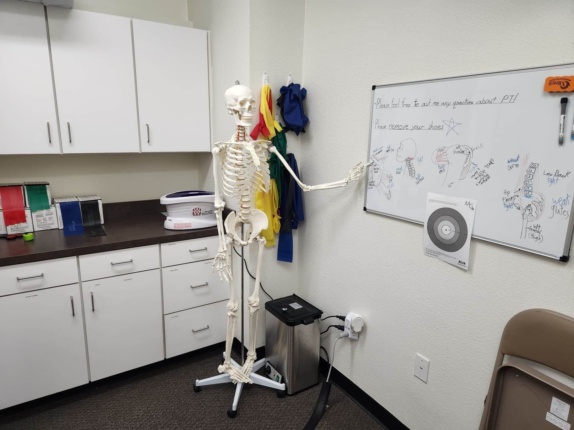 Winston is at a whiteboard in a physical therapy exam room ready to educate patients on anatomy and kinesiology