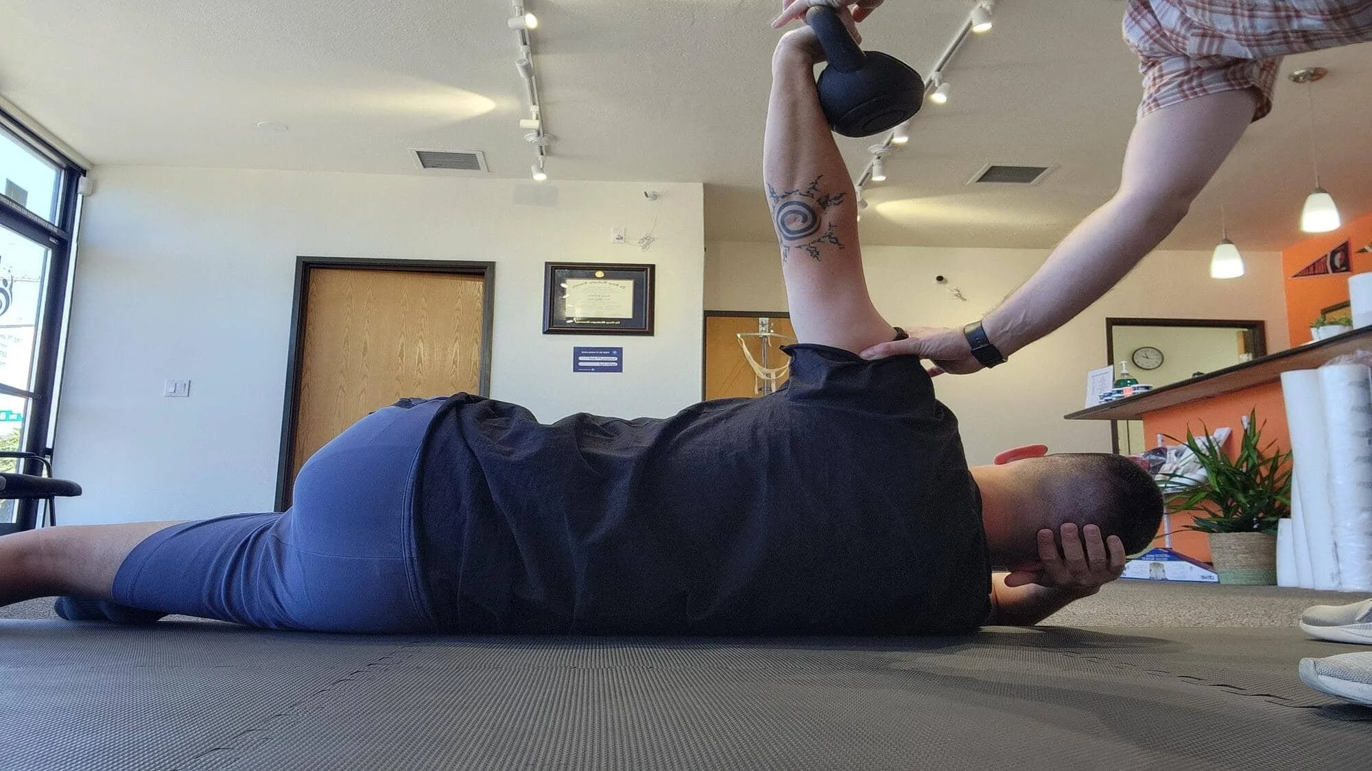 A physical therapist guides a patient through a shoulder stability exercise (arm bar).