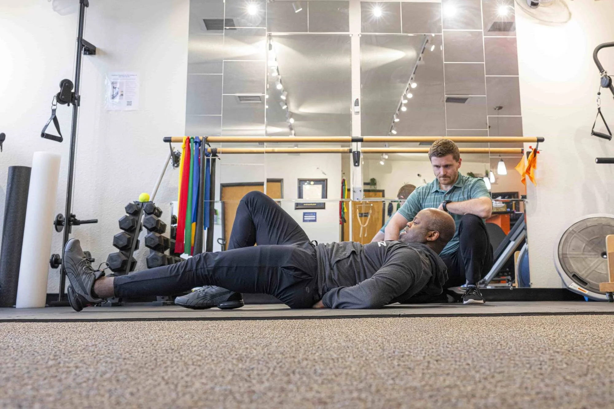 A physical therapist evaluates a patient's curl up form as a spine-sparing core exercise