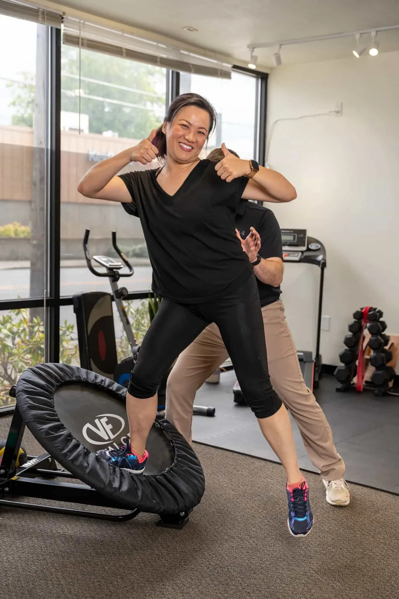 Dr. Ben guards a patient as they perform plyometric exercises off a slanted trampoline in the TVPT clinic's main area