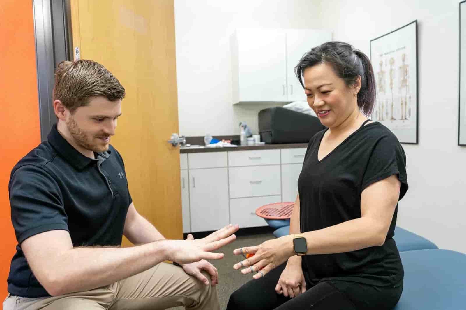 A physical therapist demonstrating a finger extension exercise to help treat tennis elbow pain