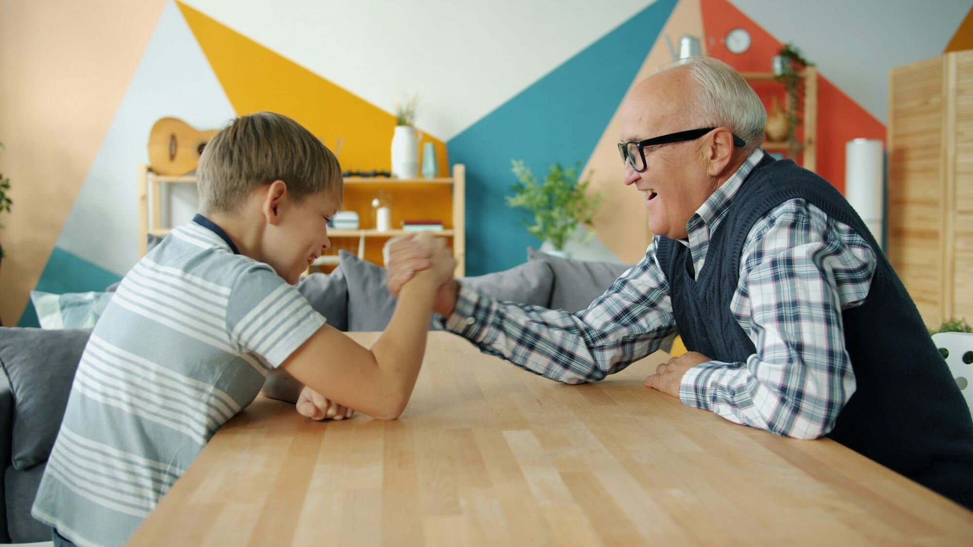 an elderly person arm-wrestling a child
