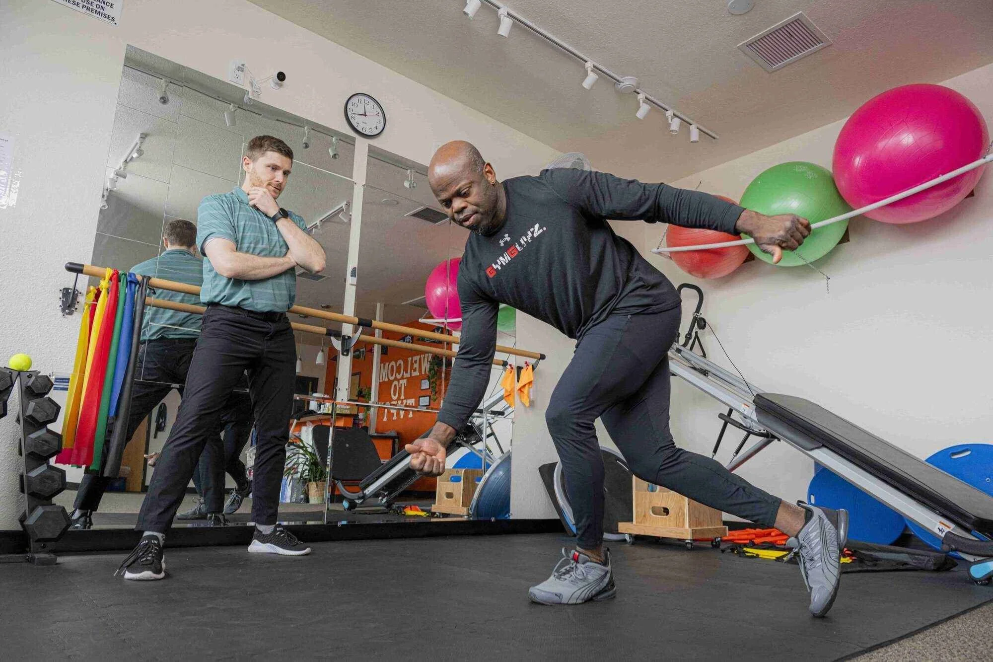 Physical therapist oversees a patient performing a bowler squat for hip stability
