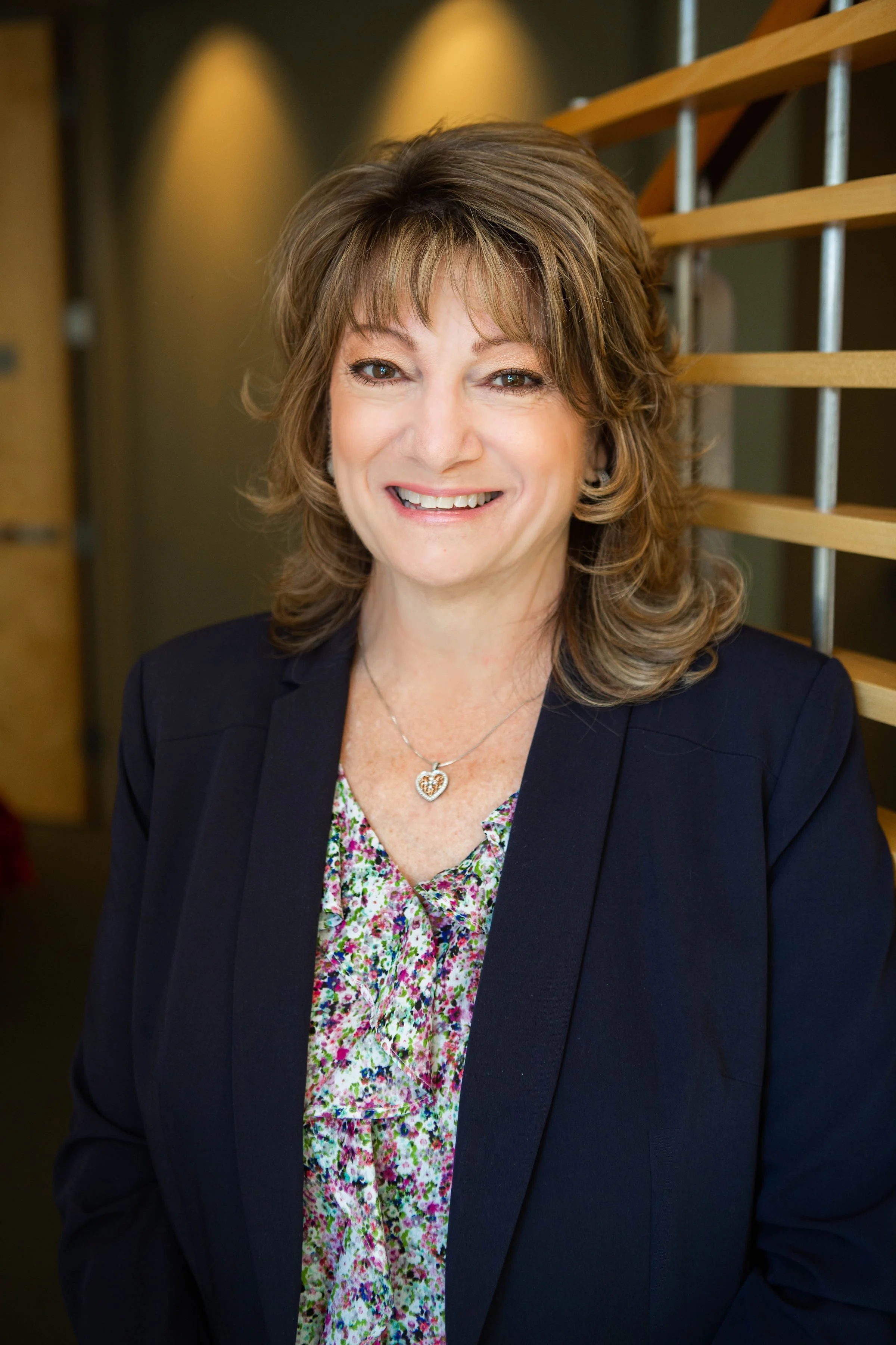 Professional headshot of smiling woman wearing dark blazer and colorful blouse