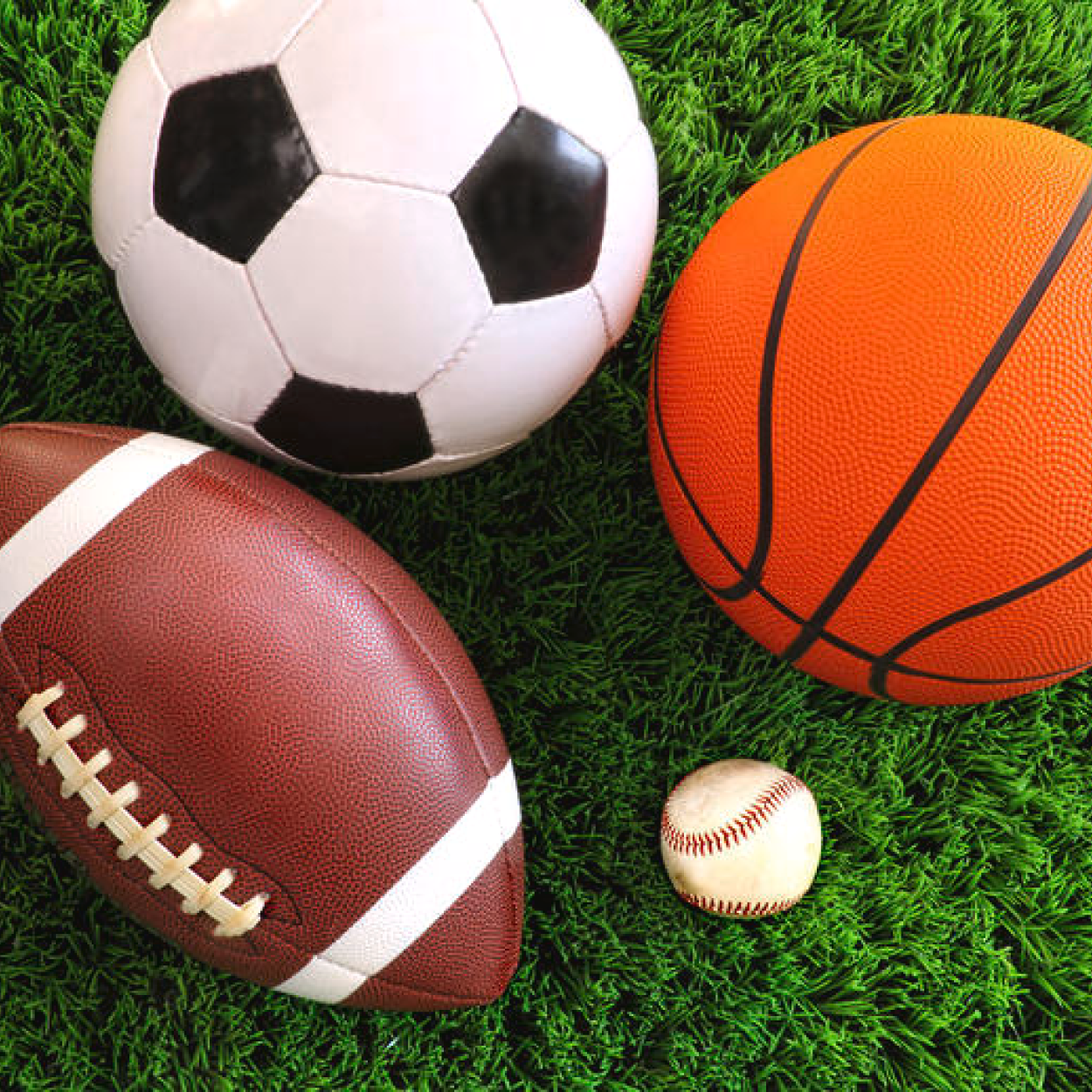 Overhead view of basketball, soccer ball, football, and baseball on grass