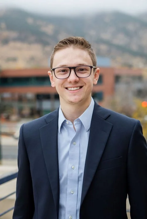 Professional headshot of man with glasses wearing a suit