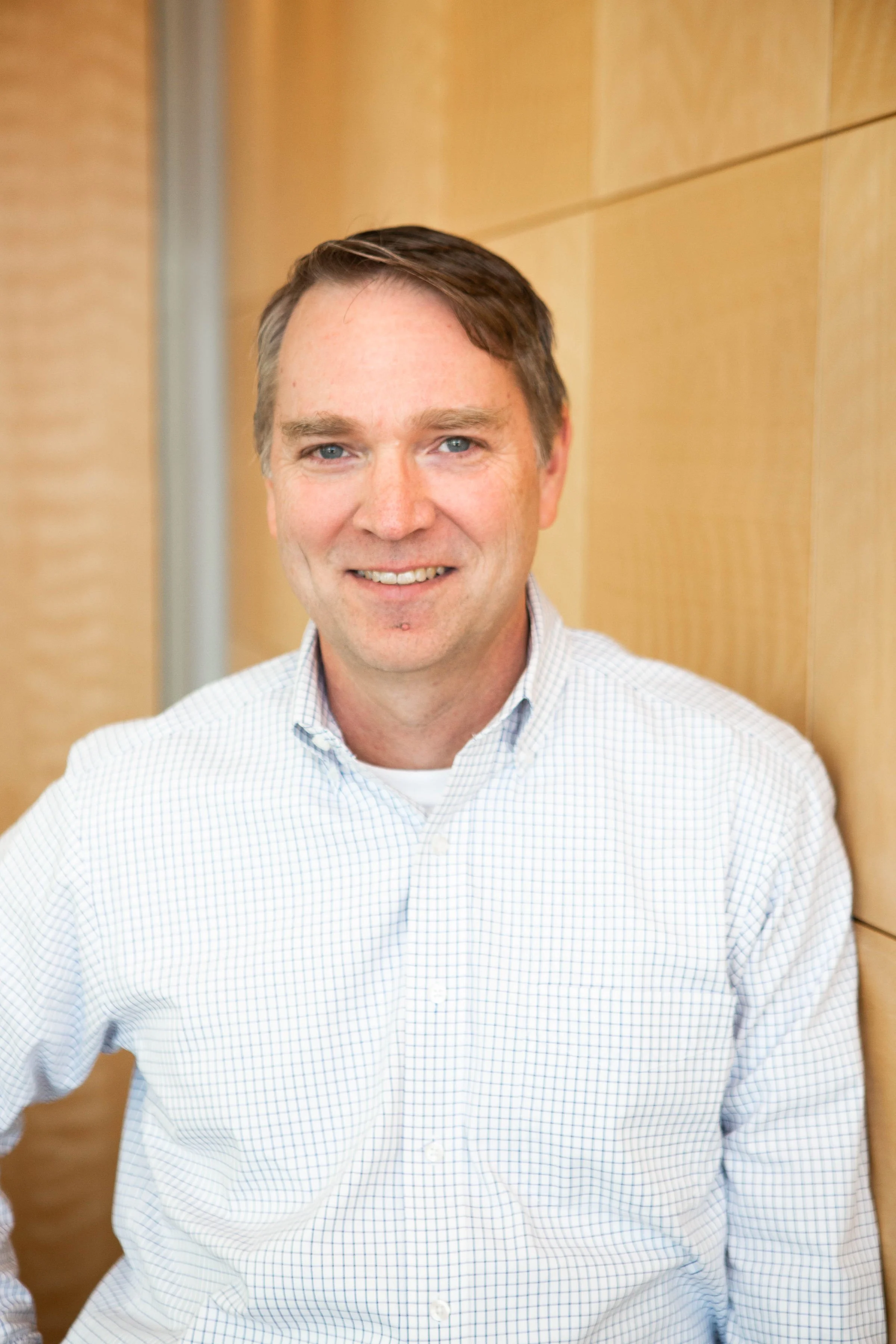 Professional headshot of man smiling in white button down shirt