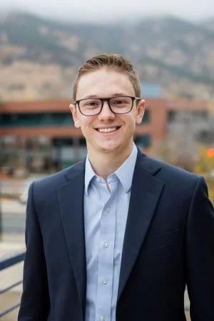Professional headshot of young man with glasses