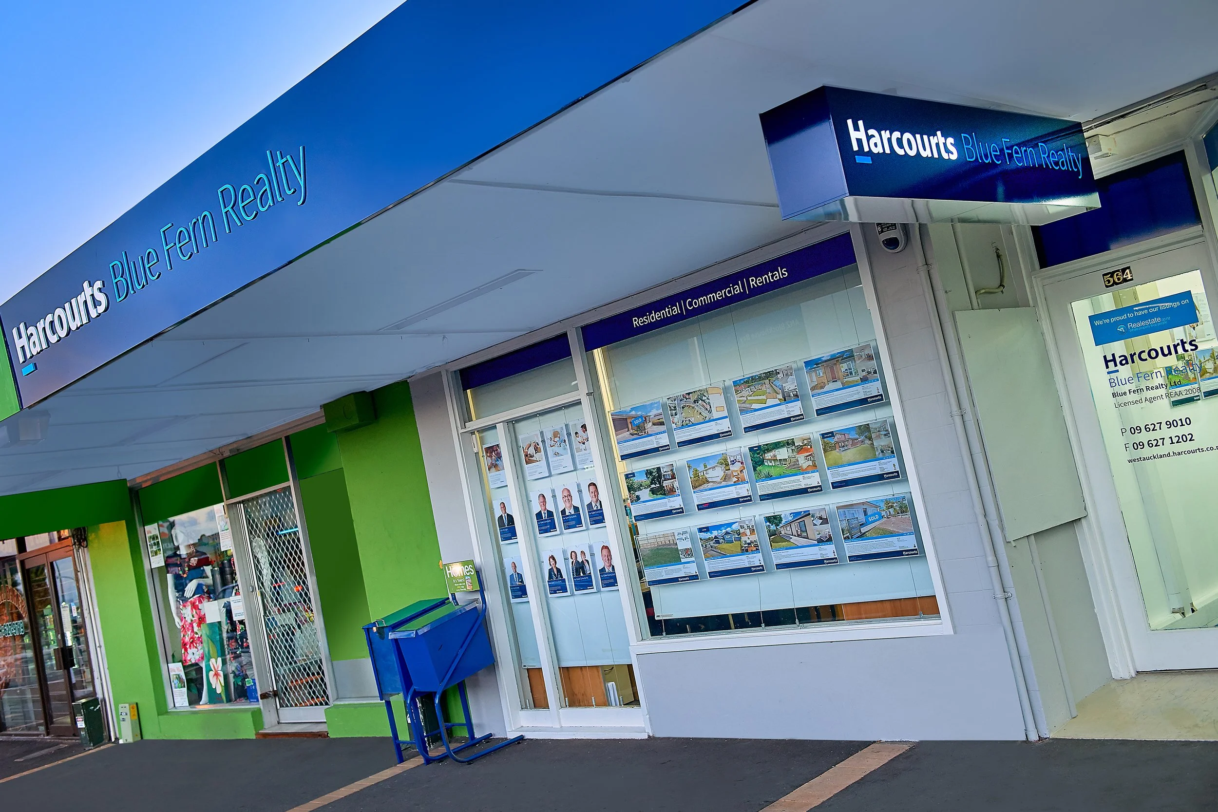 Harcourts Blue Fern Realty real estate office storefront with property listings in window display.
