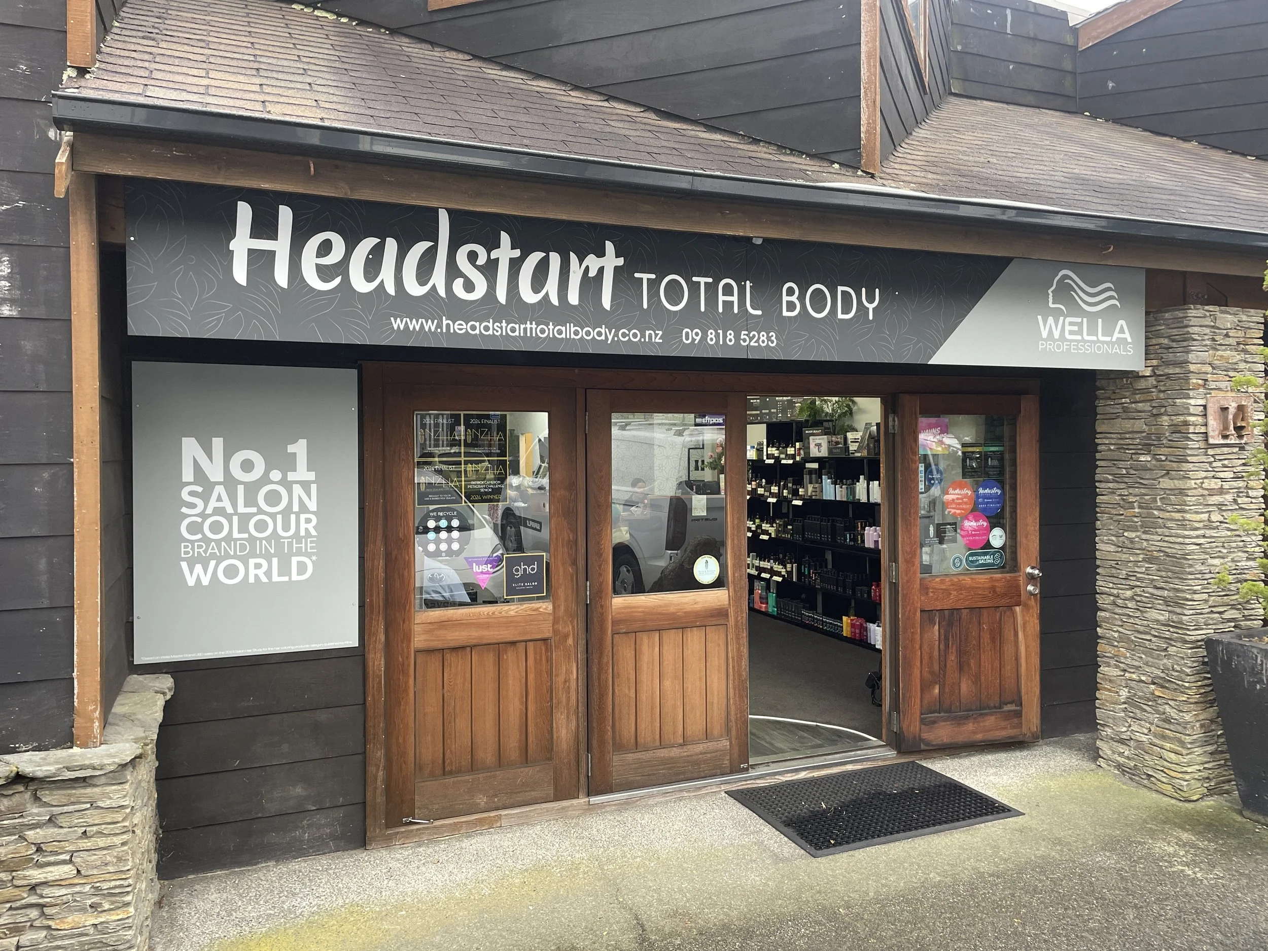Front of a salon called Headstart Total Body with wooden doors and a sign indicating it as the No.1 salon brand in the world for color.