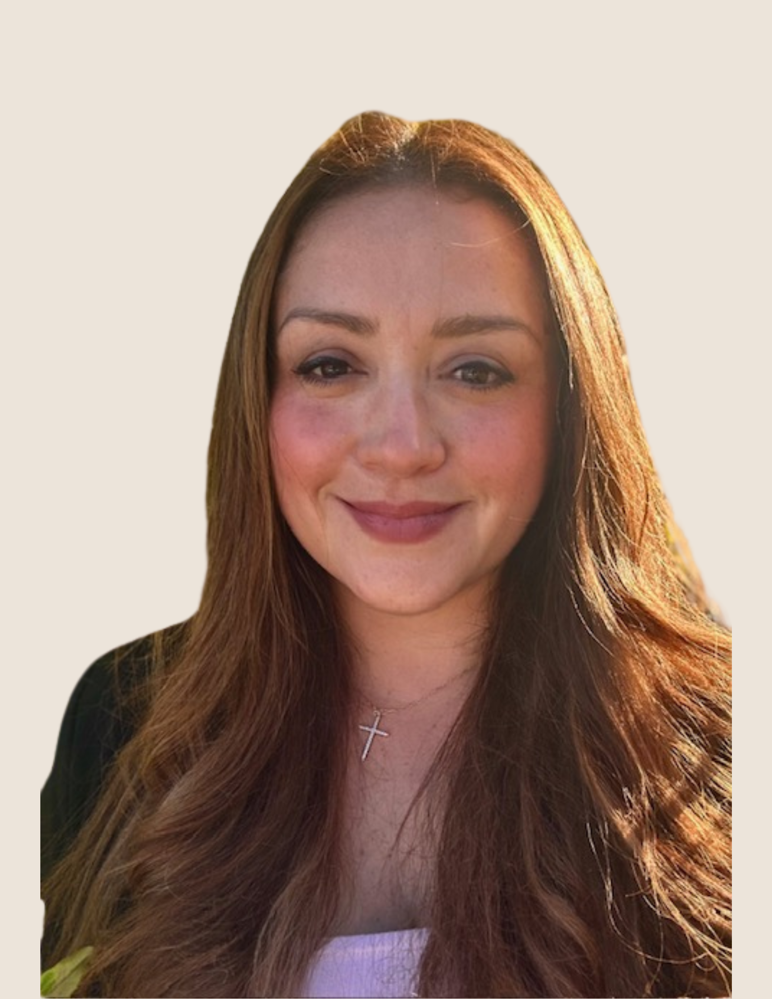 A woman with long, wavy auburn hair smiling, wearing a black top, a silver cross necklace, and natural makeup against a light beige background.