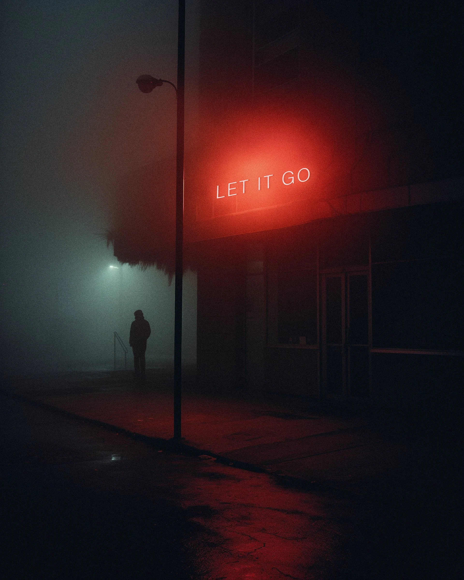A foggy street scene at night with a person walking in the distance. A neon sign on a building reads 'LET IT GO' in red.