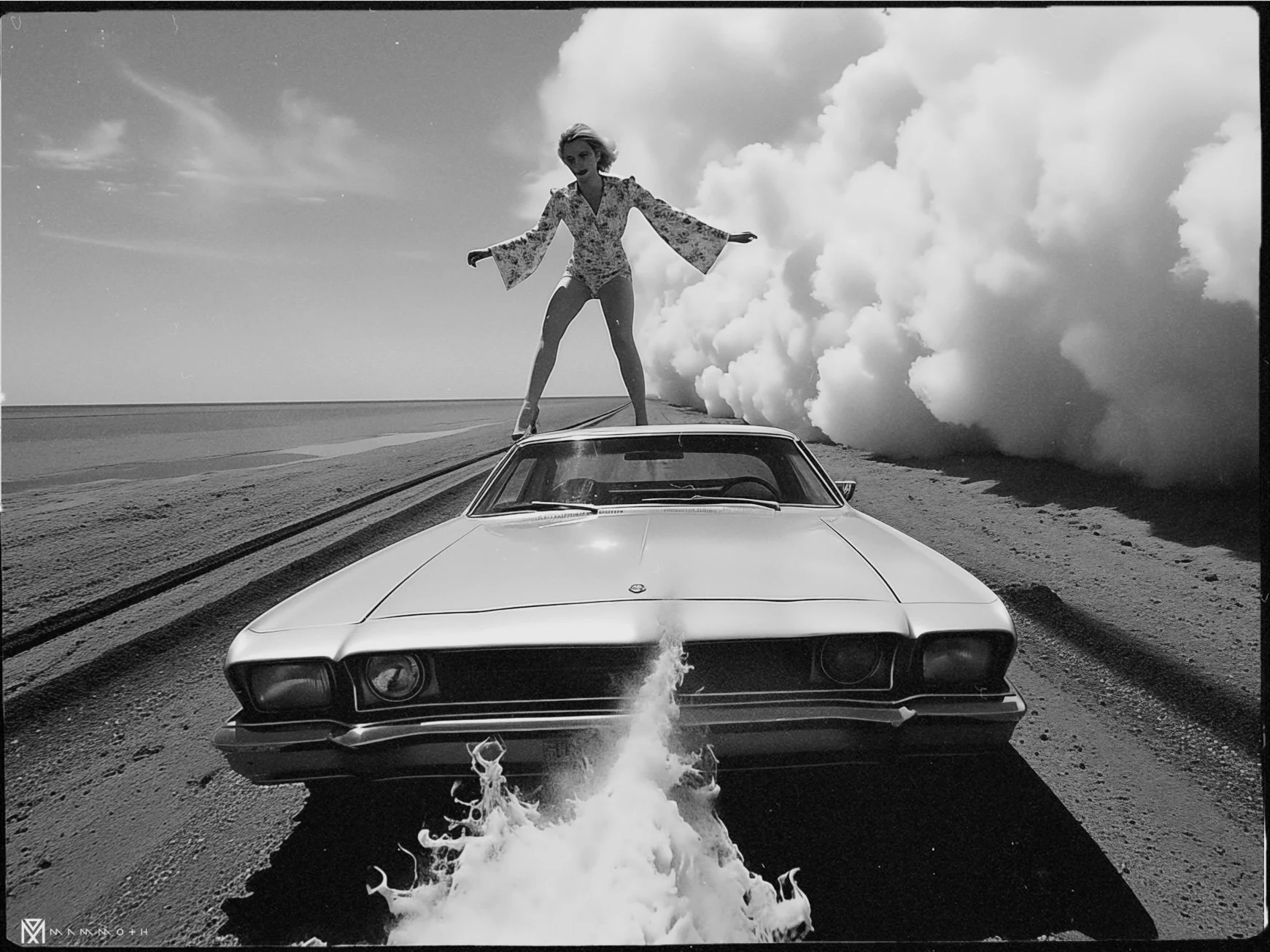 A woman standing on top of a vintage car that is on a dirt road, with large billowing clouds in the background. She is balancing with arms outstretched, wearing a floral shirt, and the car appears to be emitting smoke or steam from the front.