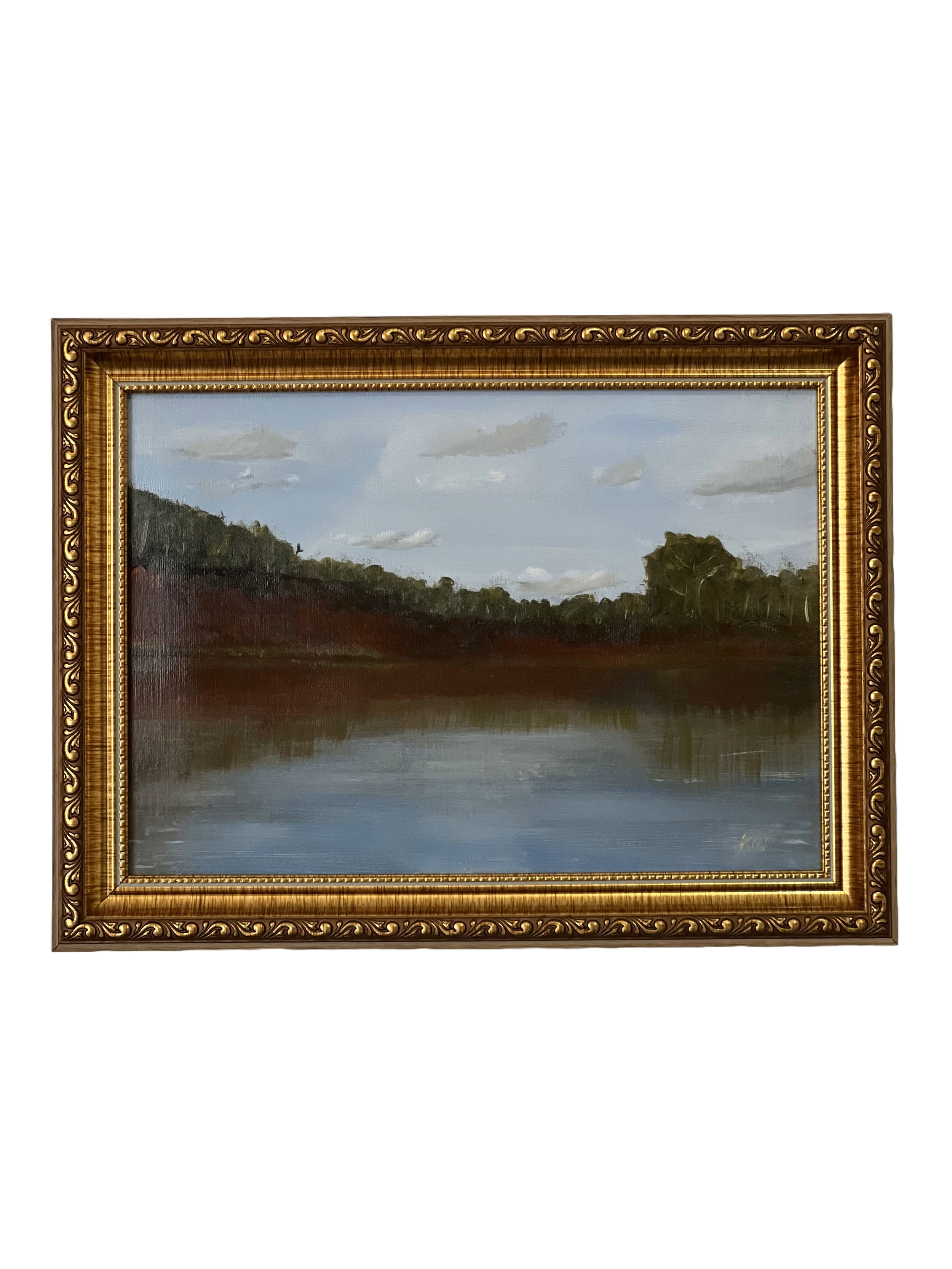 A framed landscape painting of a river scene with trees on the banks and a cloudy sky.