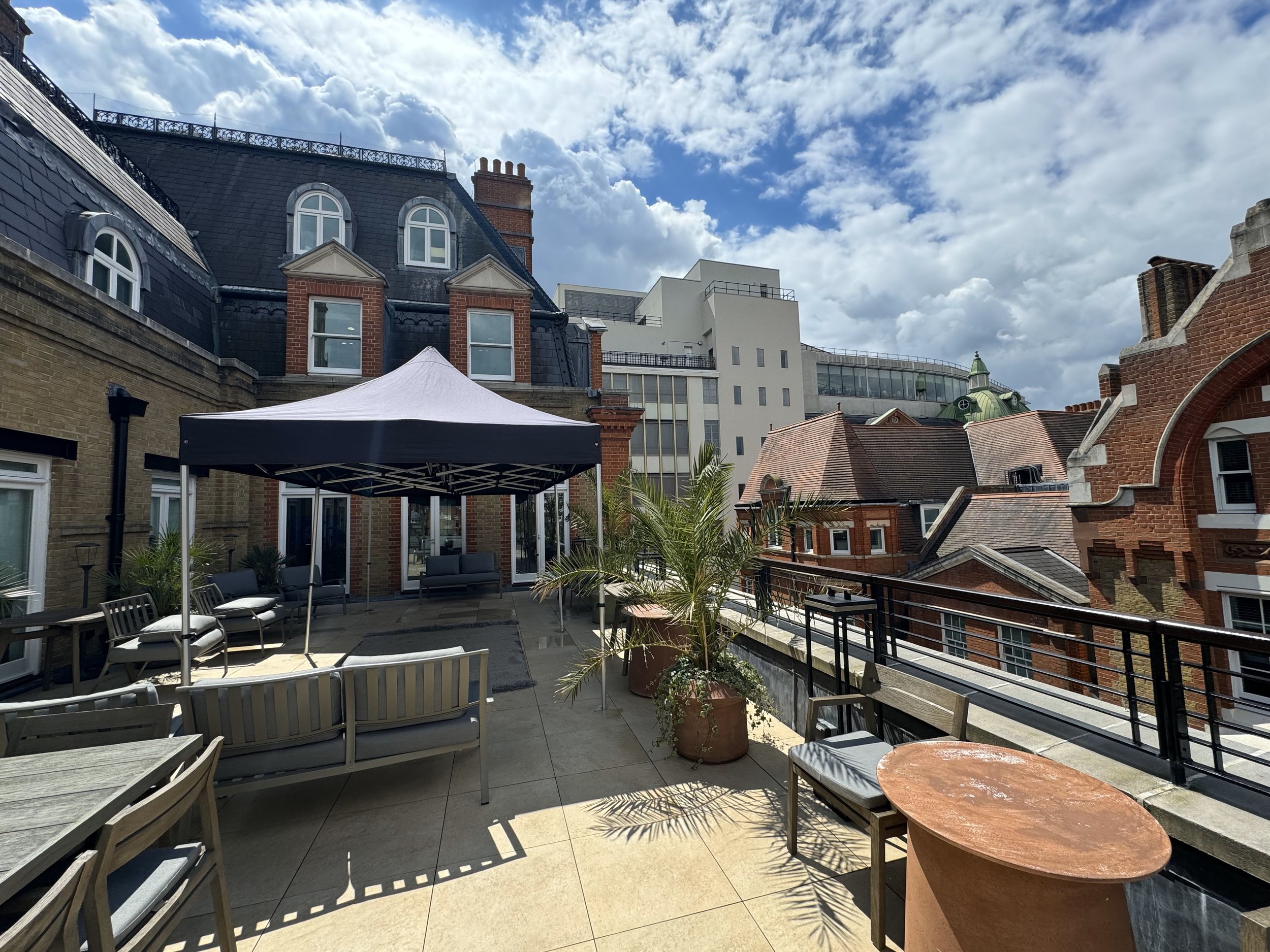 Rooftop patio with outdoor furniture, potted plants, and a white canopy, surrounded by historic and modern buildings, under partly cloudy skies. marquee hire
gazebo hire
party tent hire
party marquee hire
event tent hire
wedding marquee hire
pop up g