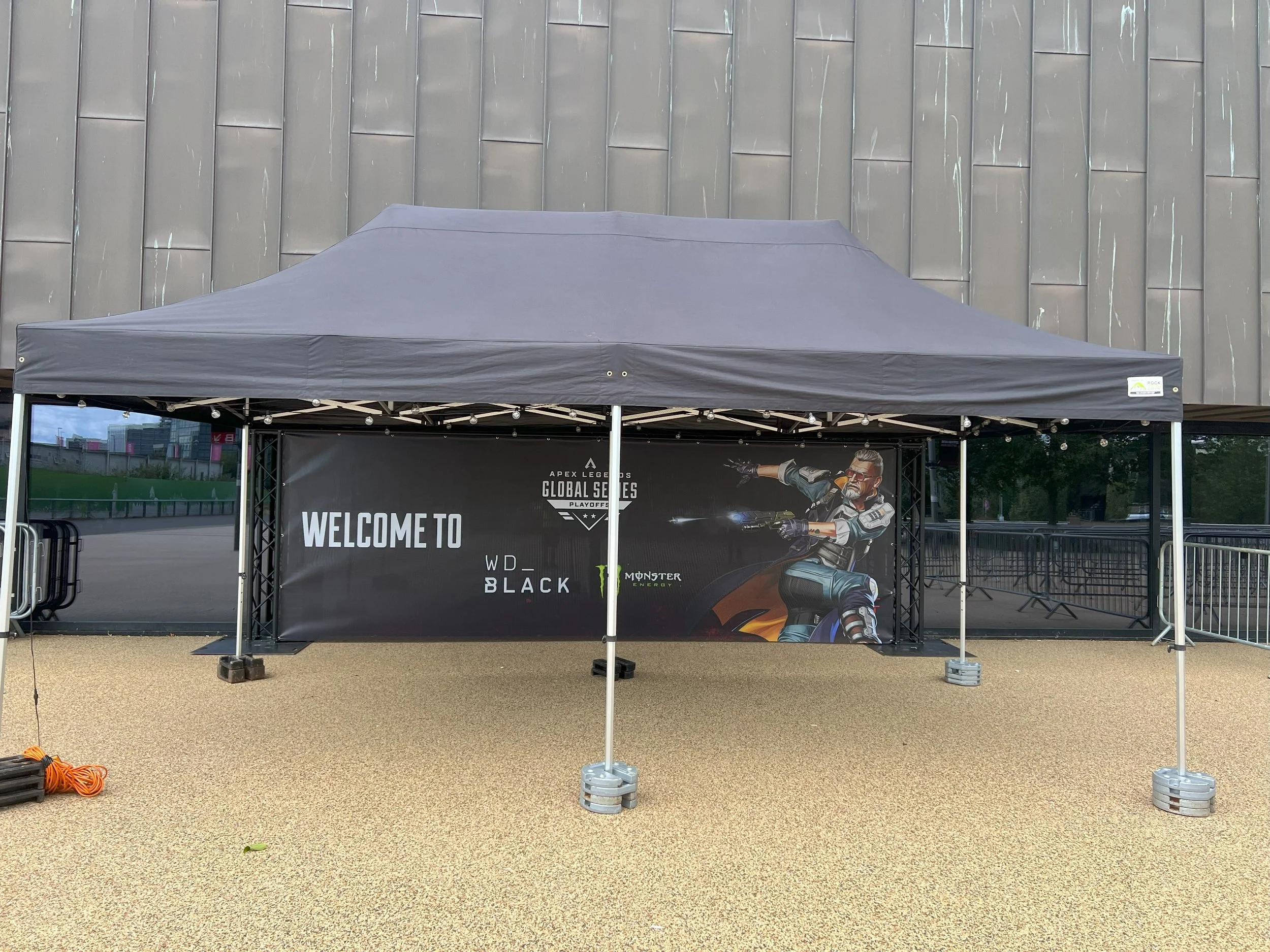 Event tent with a banner for the Apex Legends Global Series Playoffs, featuring a futuristic character in combat gear aiming a gun, next to logos of WD_BLACK and Monster Energy. marquee hire
gazebo hire
party tent hire
party marquee hire
event tent h
