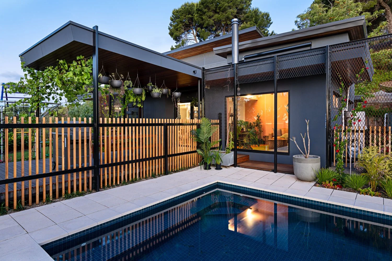 Rear view of the house from the pool area. The pool fence is wooden.