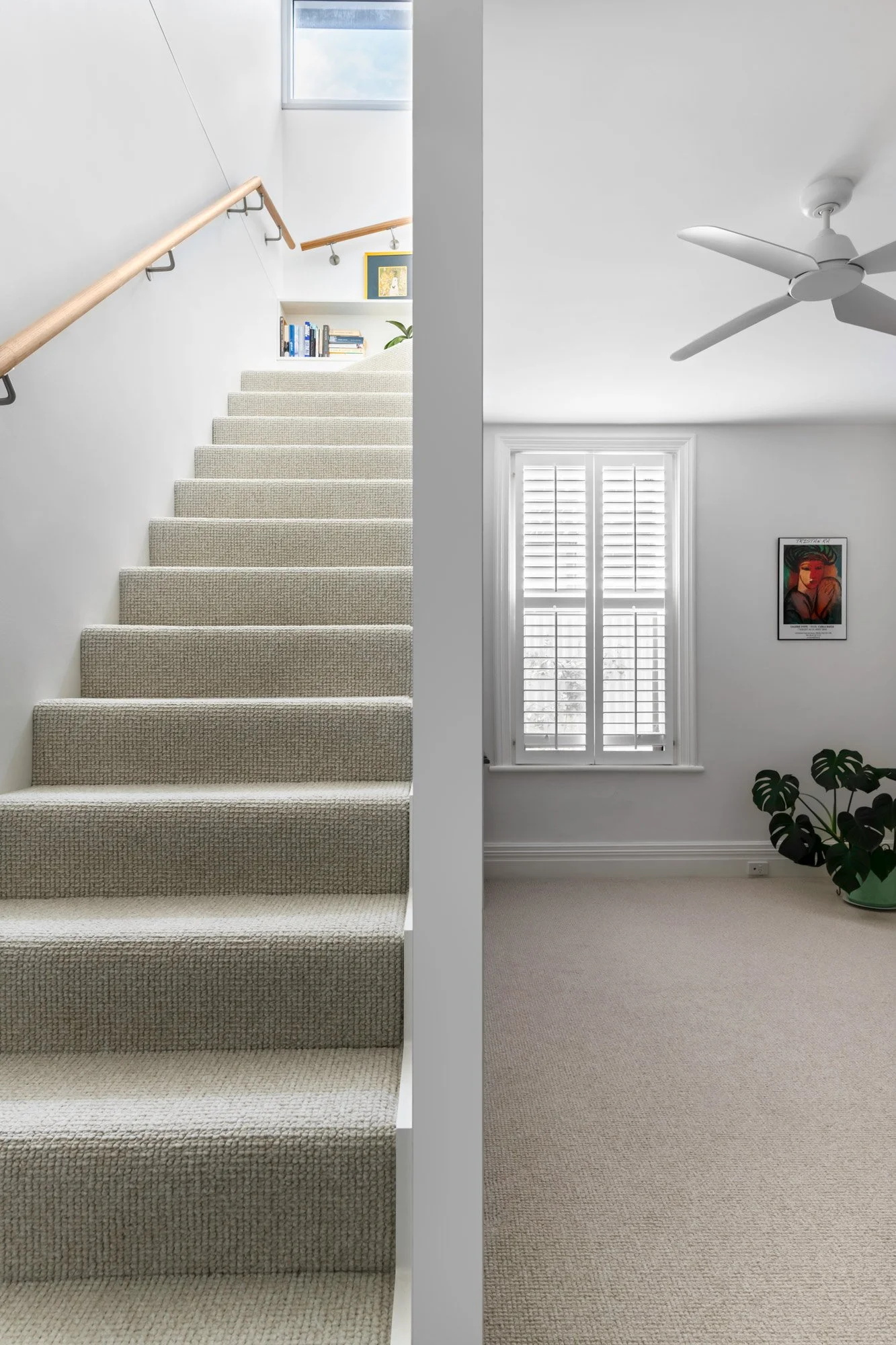 An edge-on view of a white floor-to-ceiling slat centered perfectly in the image, creating a deliberate boundary that separates the modern staircase from the Edwardian living area.