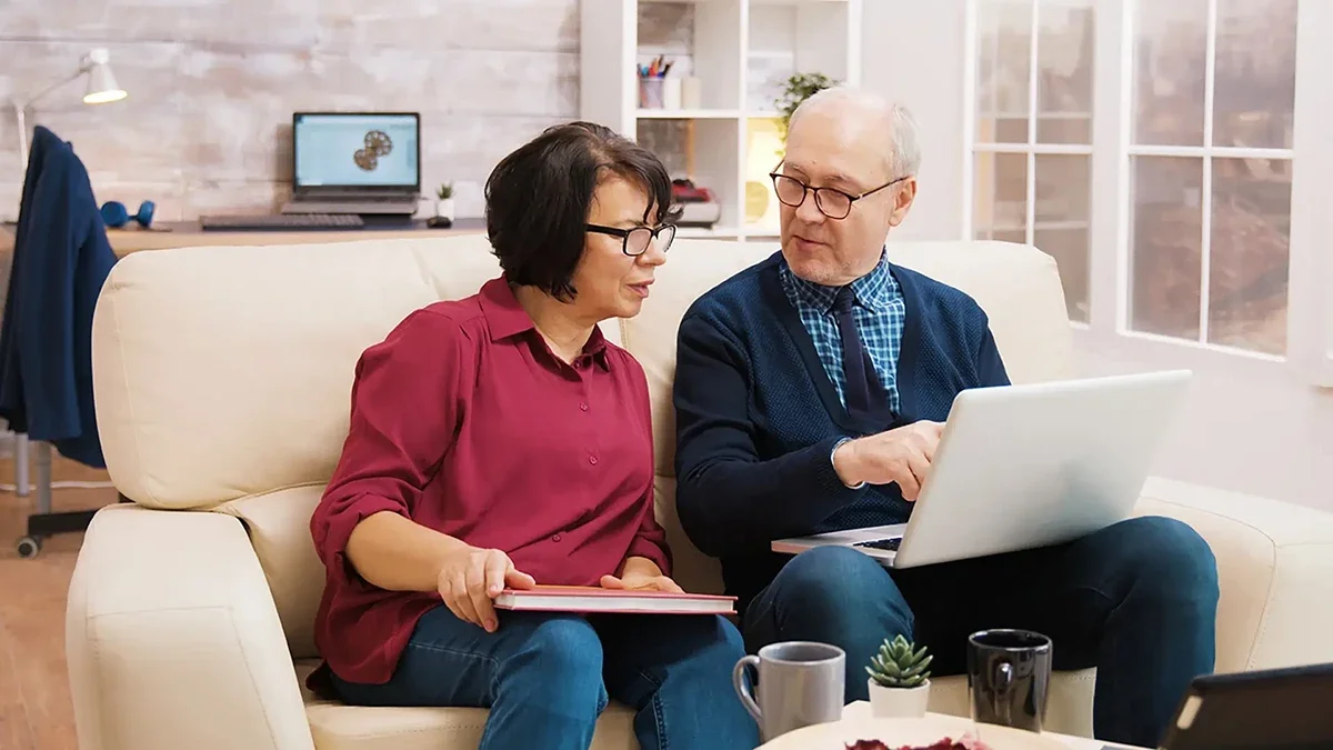 Older couple looking at a computer together while exploring caring senior moving and relocation services.