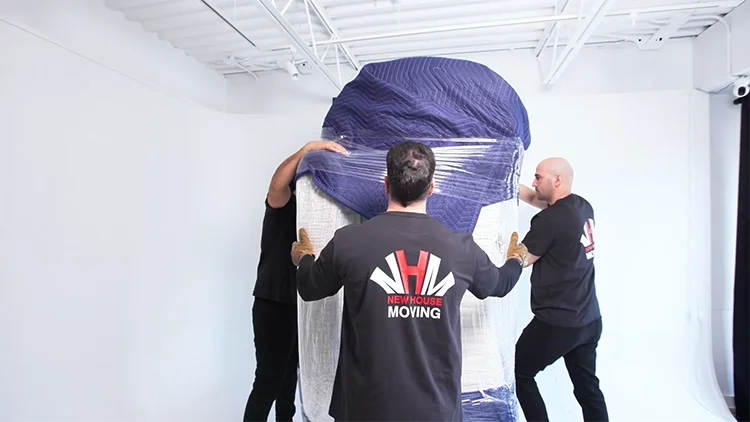 Professional movers carefully wrapping and delivering large furniture with protective blankets for safe transport in Toronto.