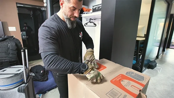 Two professional movers in dark uniforms carefully transporting furniture from one room to another—showcasing efficient and organized internal moving services.